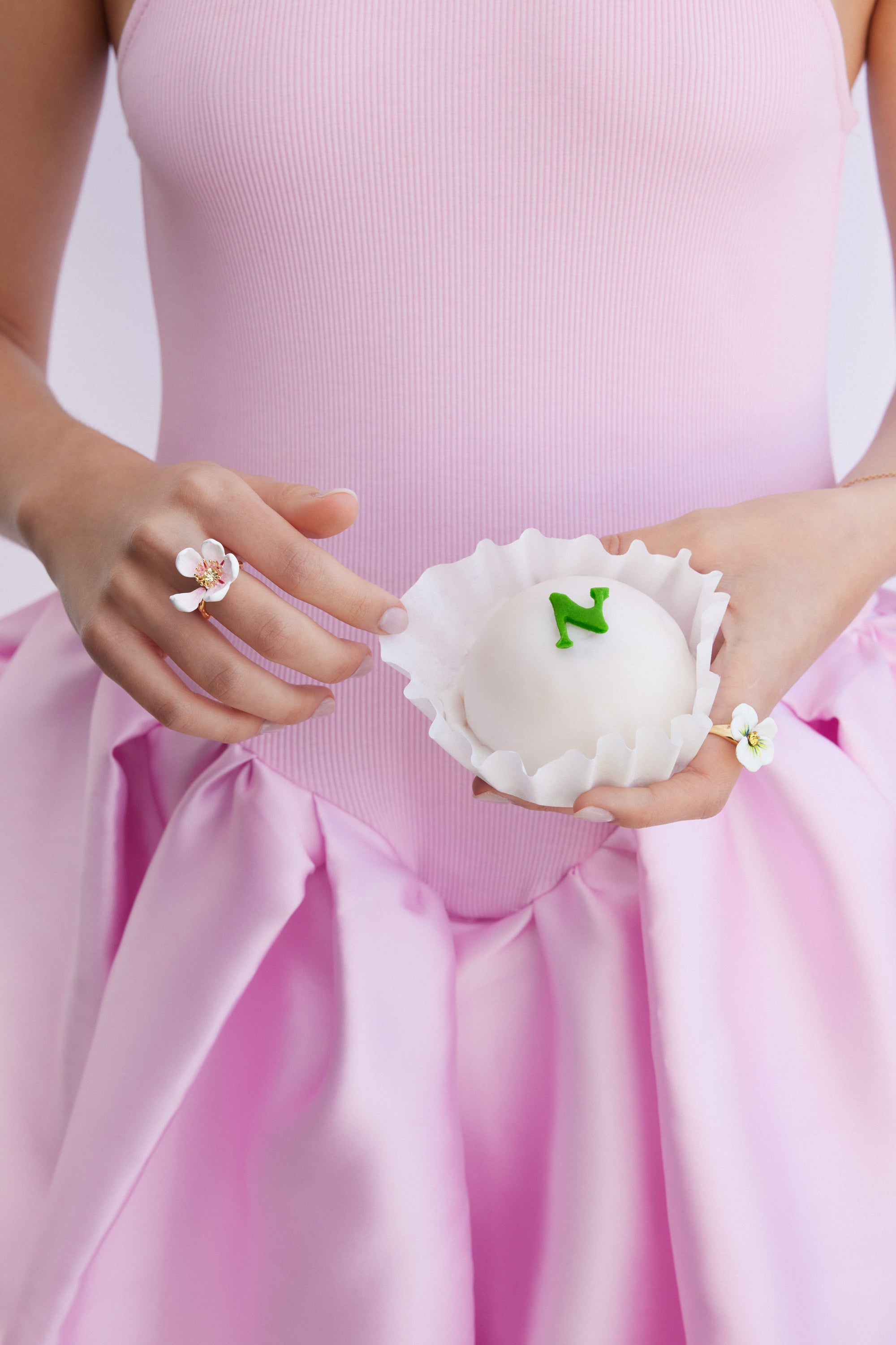 Gold-toned ring with a white multi-petal flower design, featuring a gold-toned center with small pink details.