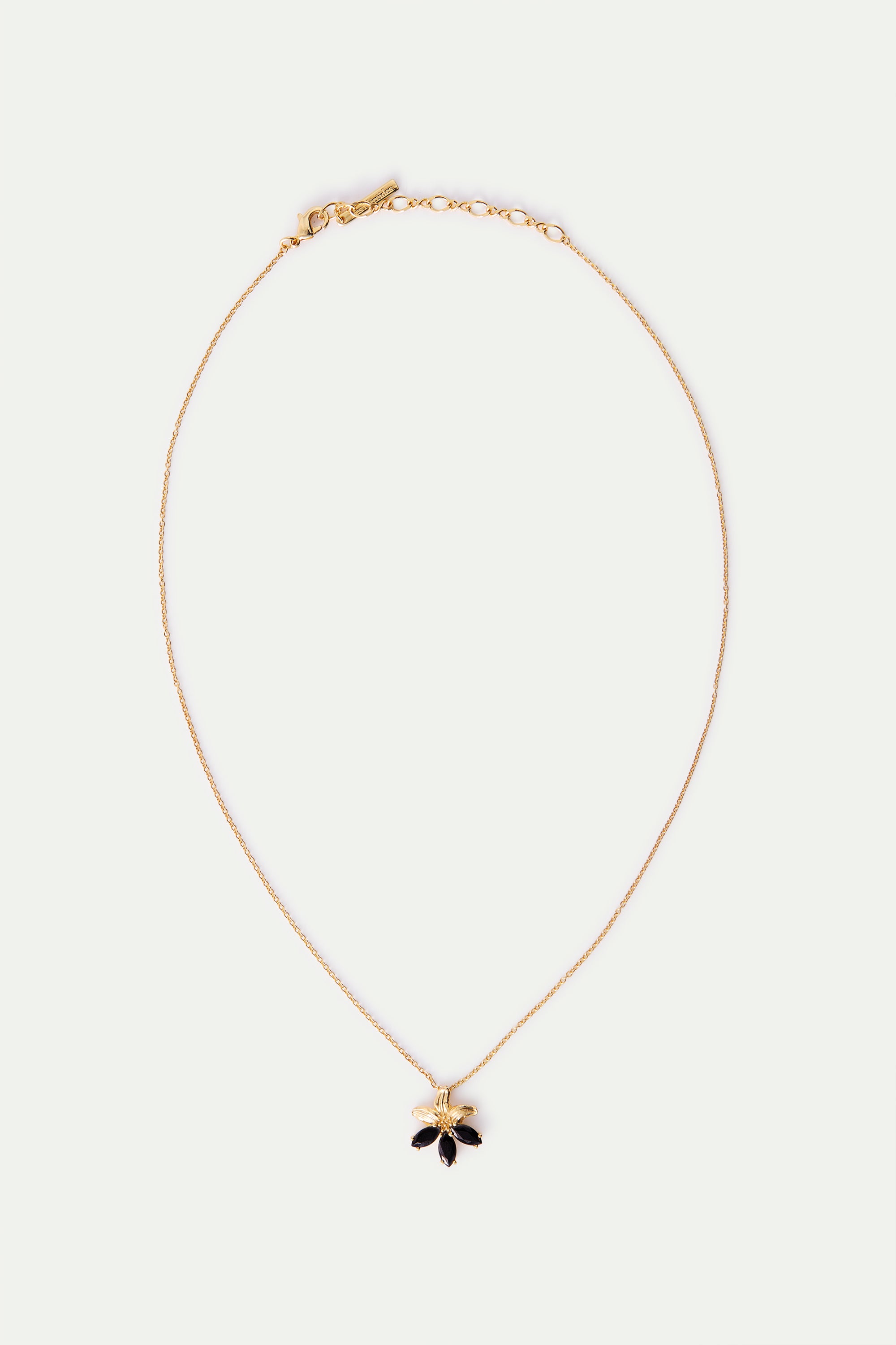 Gold-toned necklace with a flower pendant featuring three black marquise-shaped petals and a gold-toned petal.