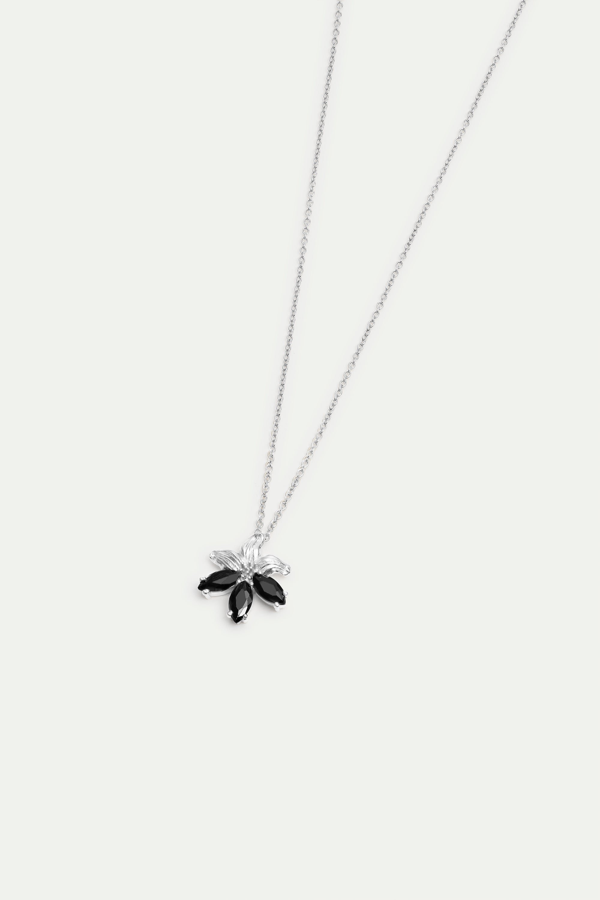 Silver-toned necklace with a floral pendant featuring three black marquise-cut stones and two clear marquise-cut stones.