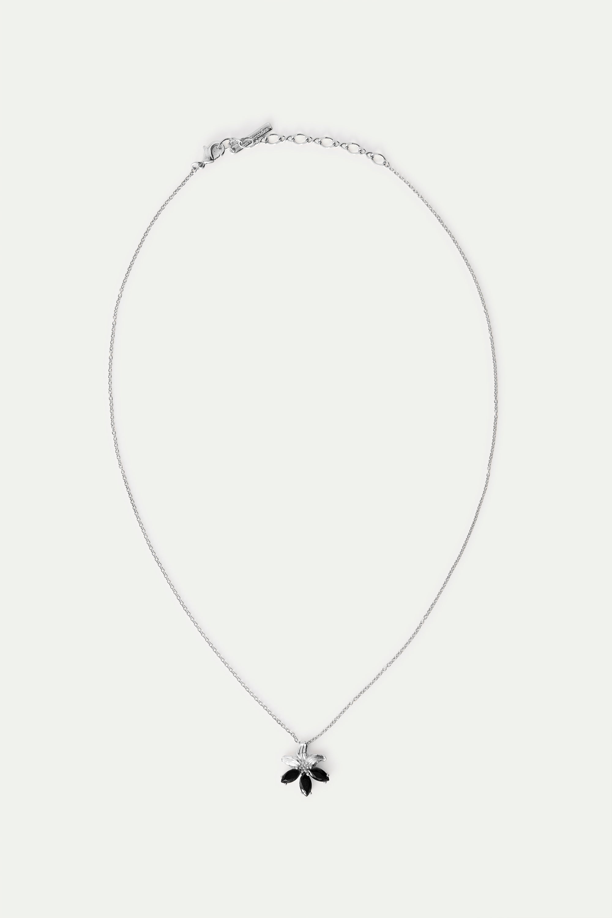 Silver-toned necklace with a delicate chain and a flower pendant featuring three black and two clear marquise-shaped petals.