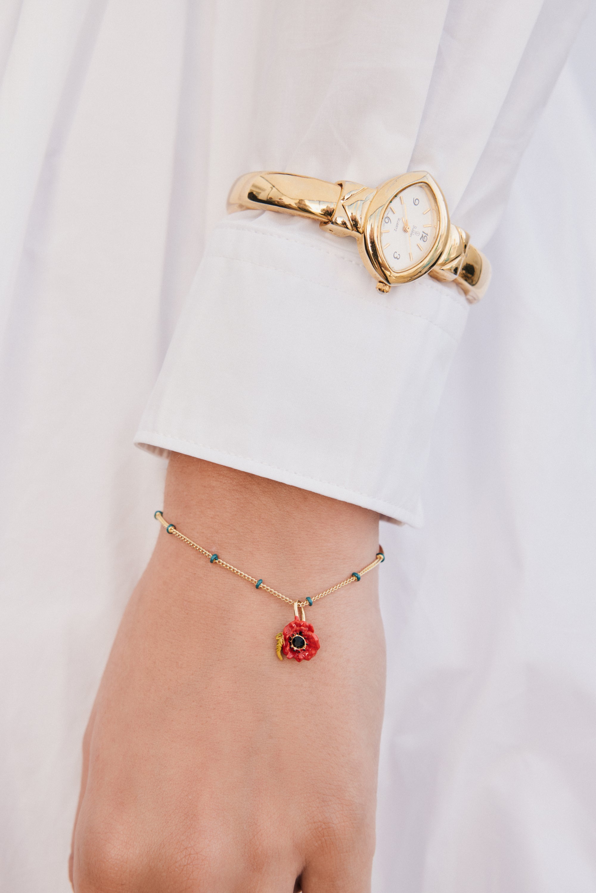 Gold-toned chain bracelet with small teal beads and a red poppy charm with a black center and yellow details.