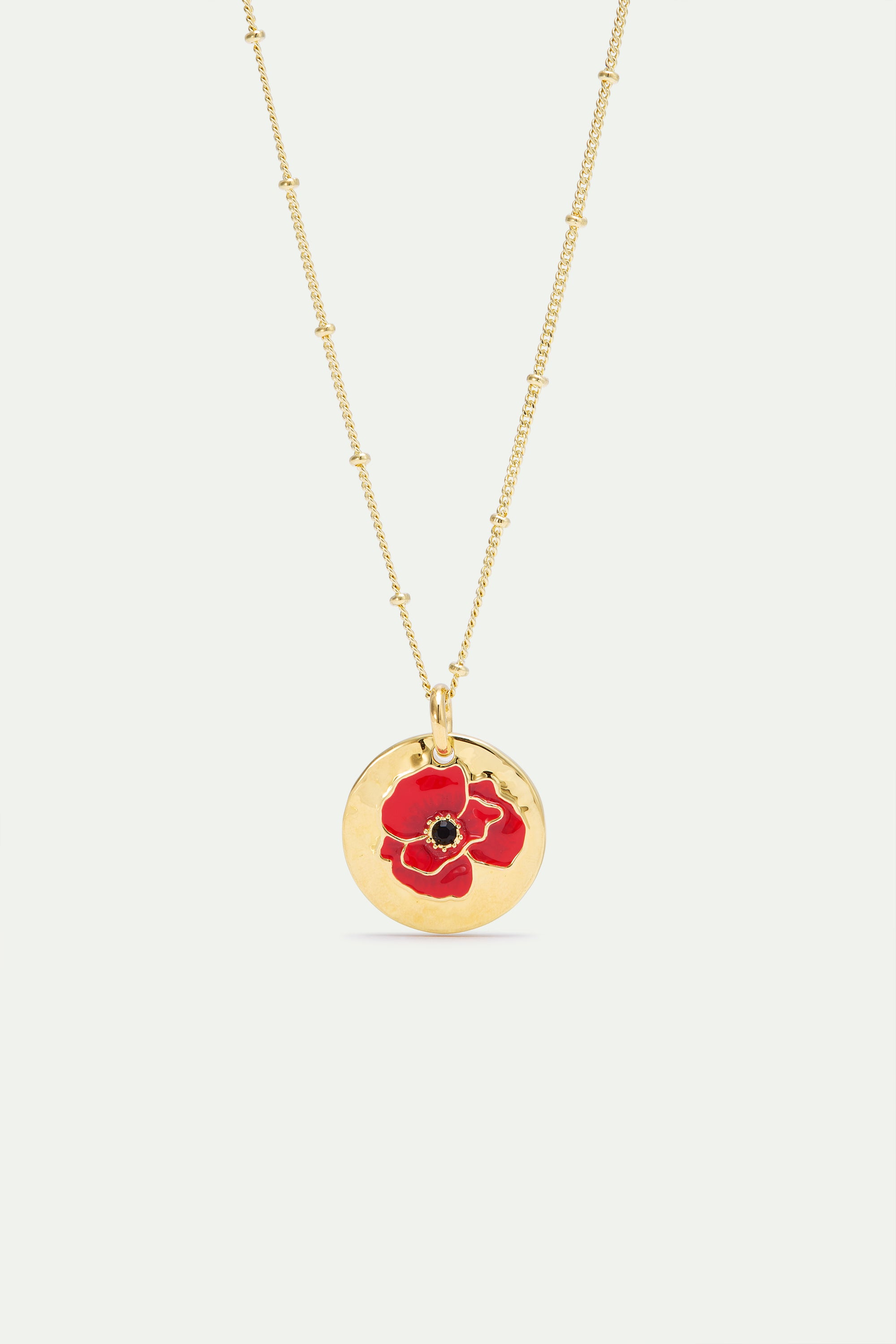 Gold-toned satellite chain necklace with a round, hammered gold-toned pendant featuring a red and black enamel poppy.