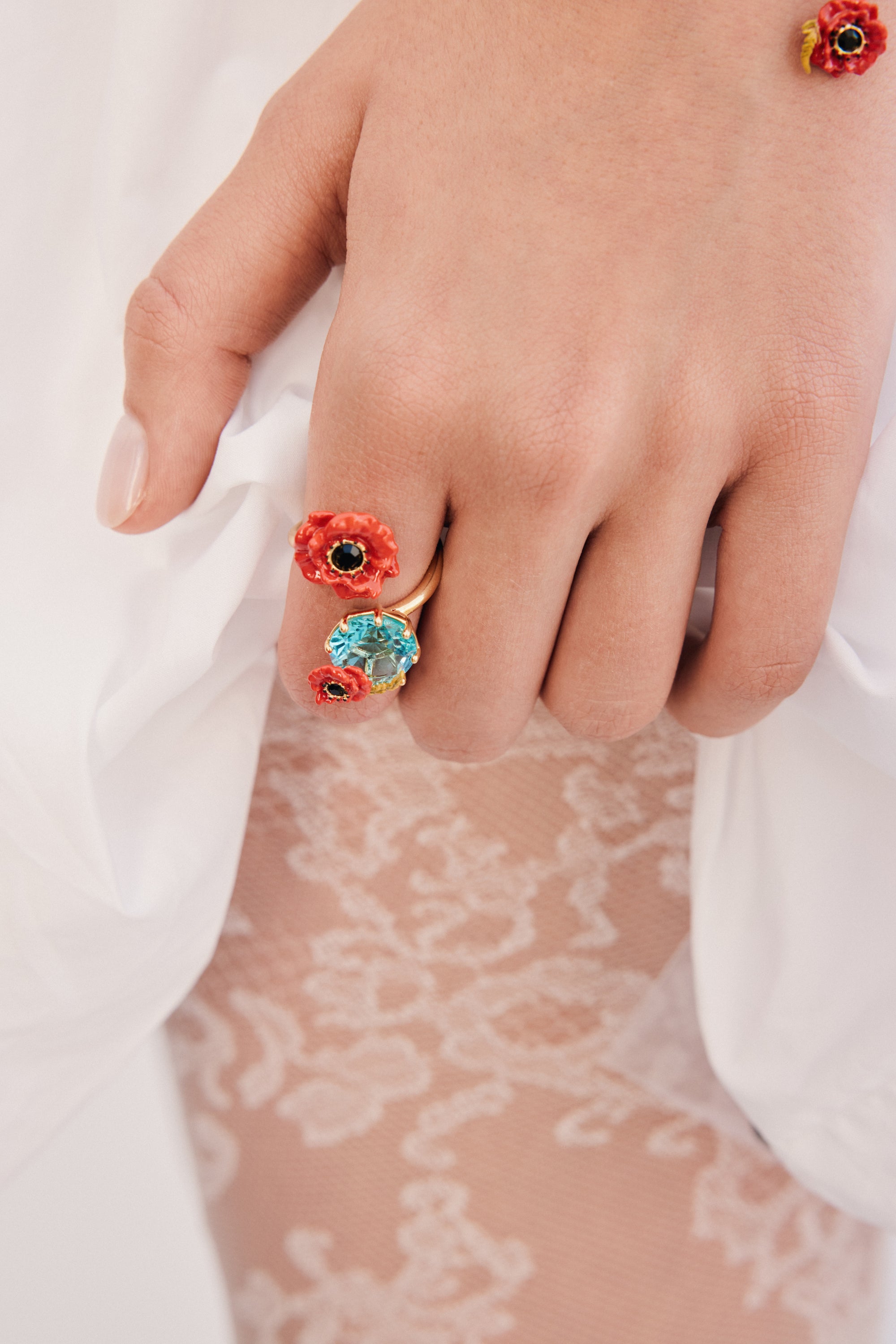 Gold-toned adjustable ring with a large red poppy with black center, a light blue oval gemstone, and a small red poppy.