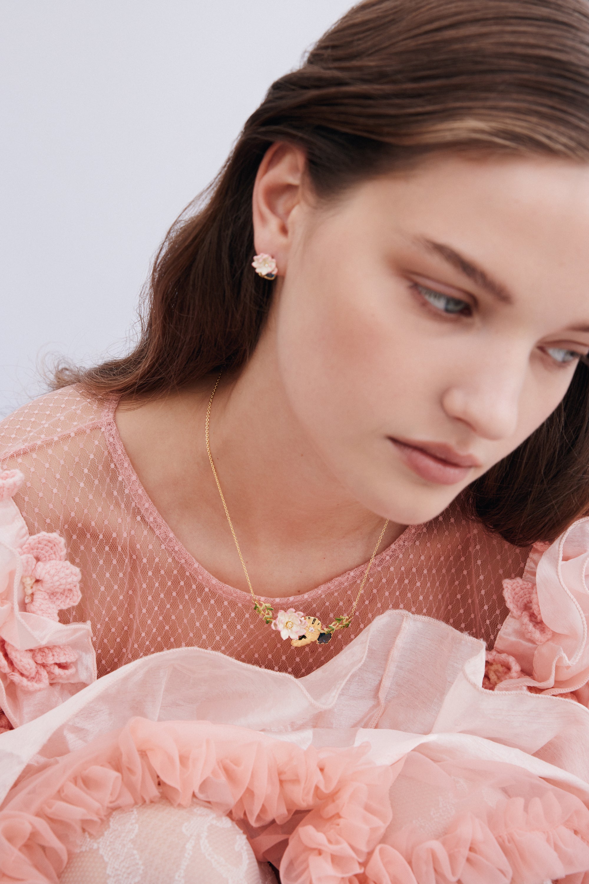 A single pale pink flower post earring with a gold-toned base and delicate petals.
