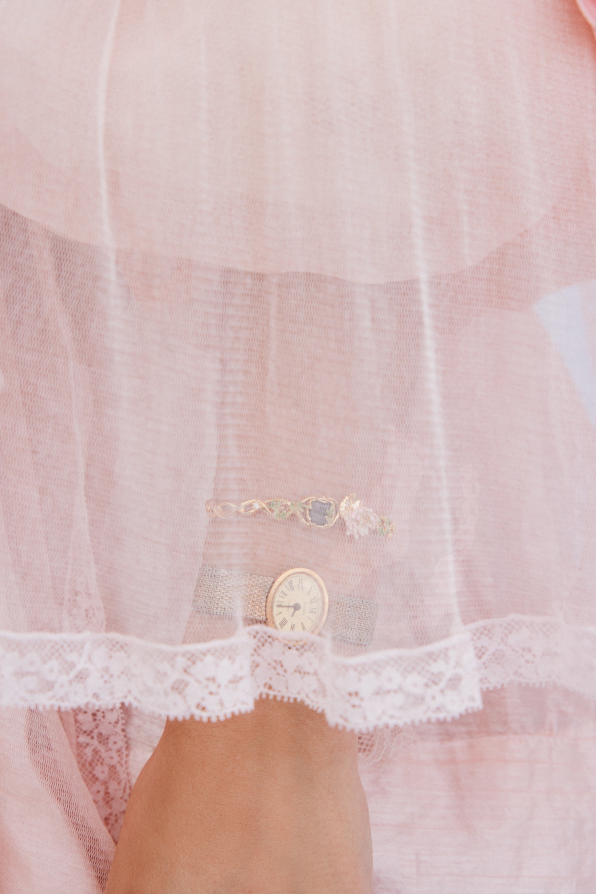 Gold-toned cuff bracelet with a twisted band, featuring light green leaf-like accents, a central muted blue square stone, and