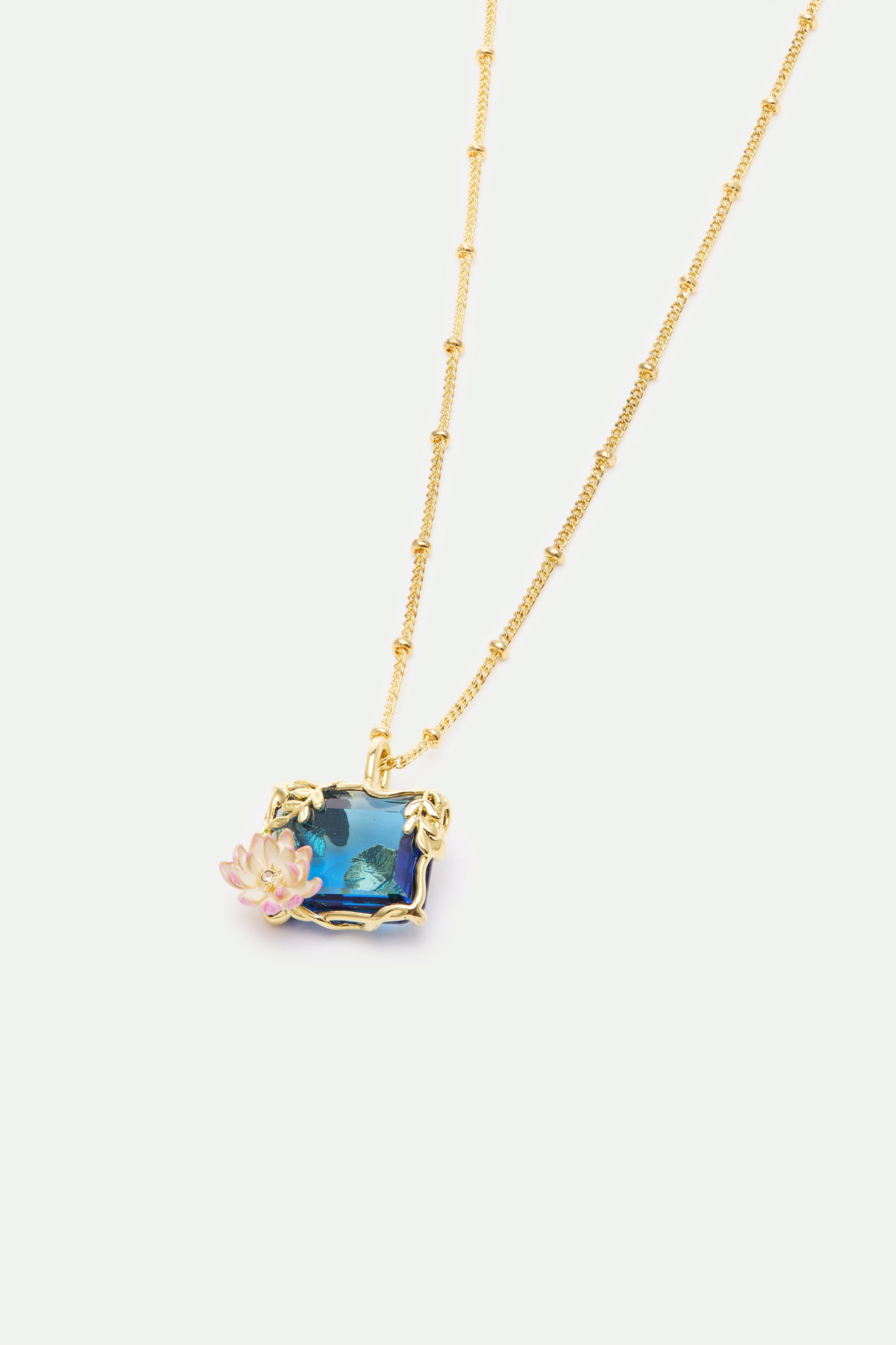 Gold-toned beaded chain necklace with a rectangular blue pendant featuring water lilies, framed by gold-toned leaves and a pi