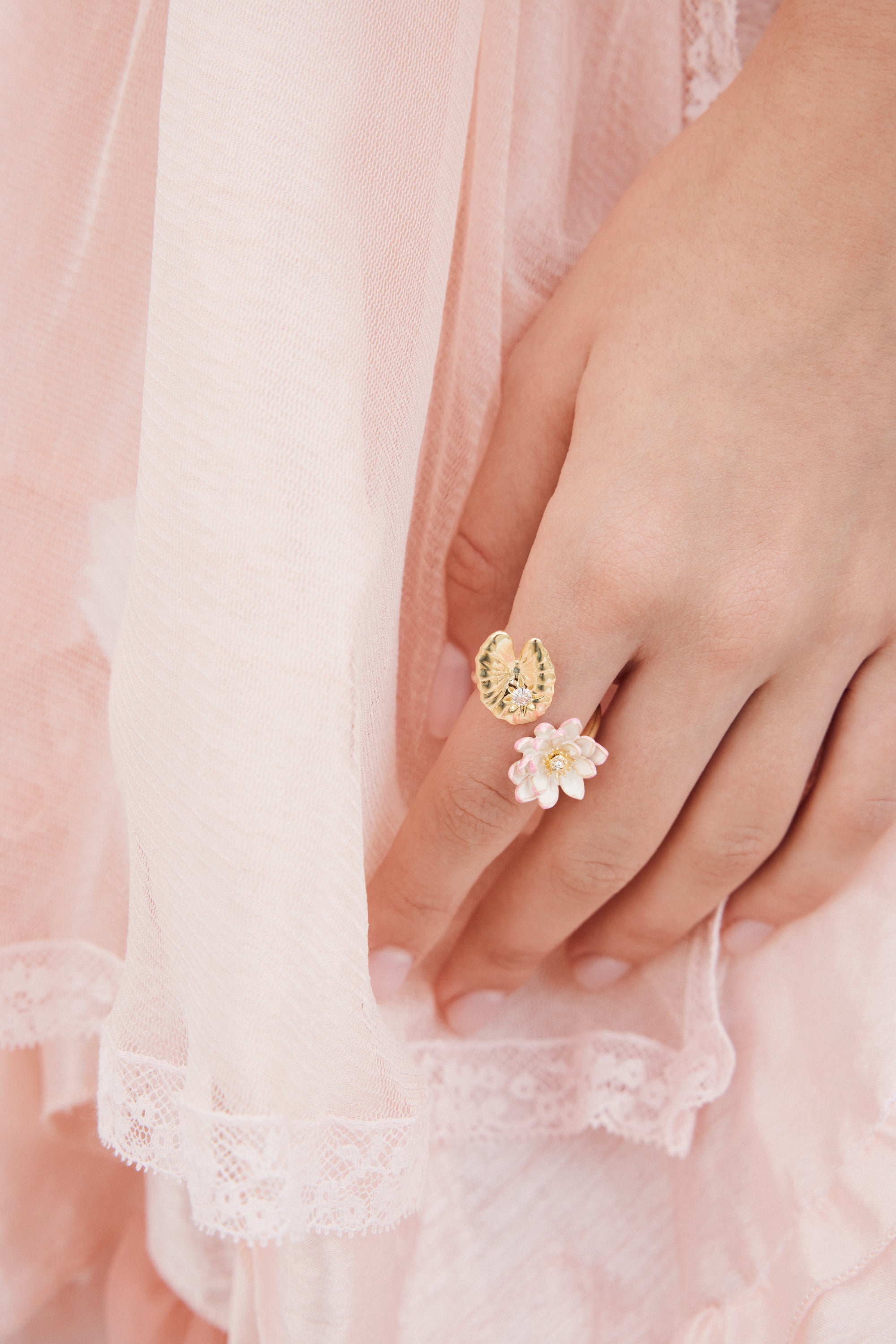 Adjustable gold-toned ring with a textured lily pad and a white and pink water lily flower, each with a clear stone.