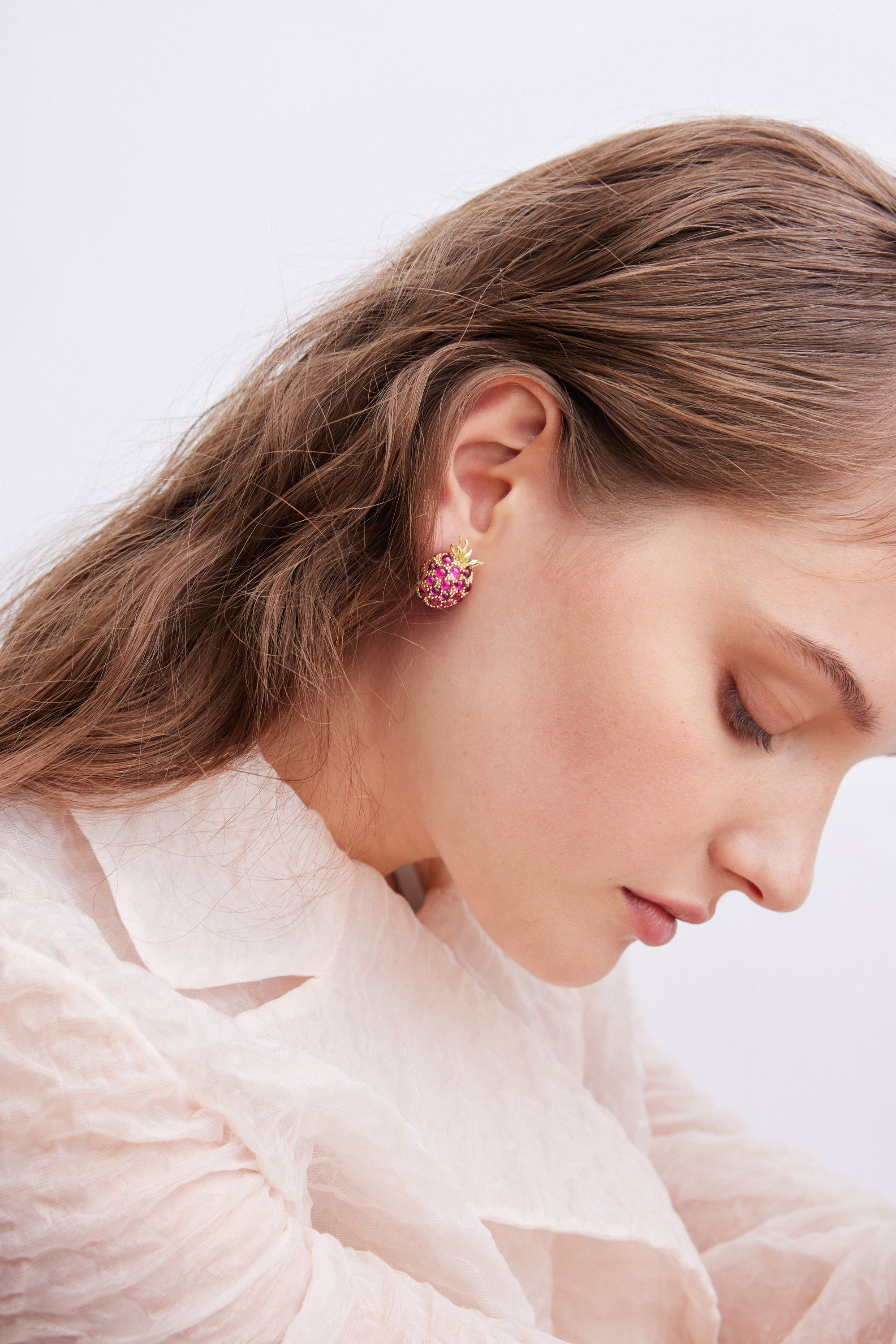 A single gold-toned pineapple post earring, its body covered in pink stones.