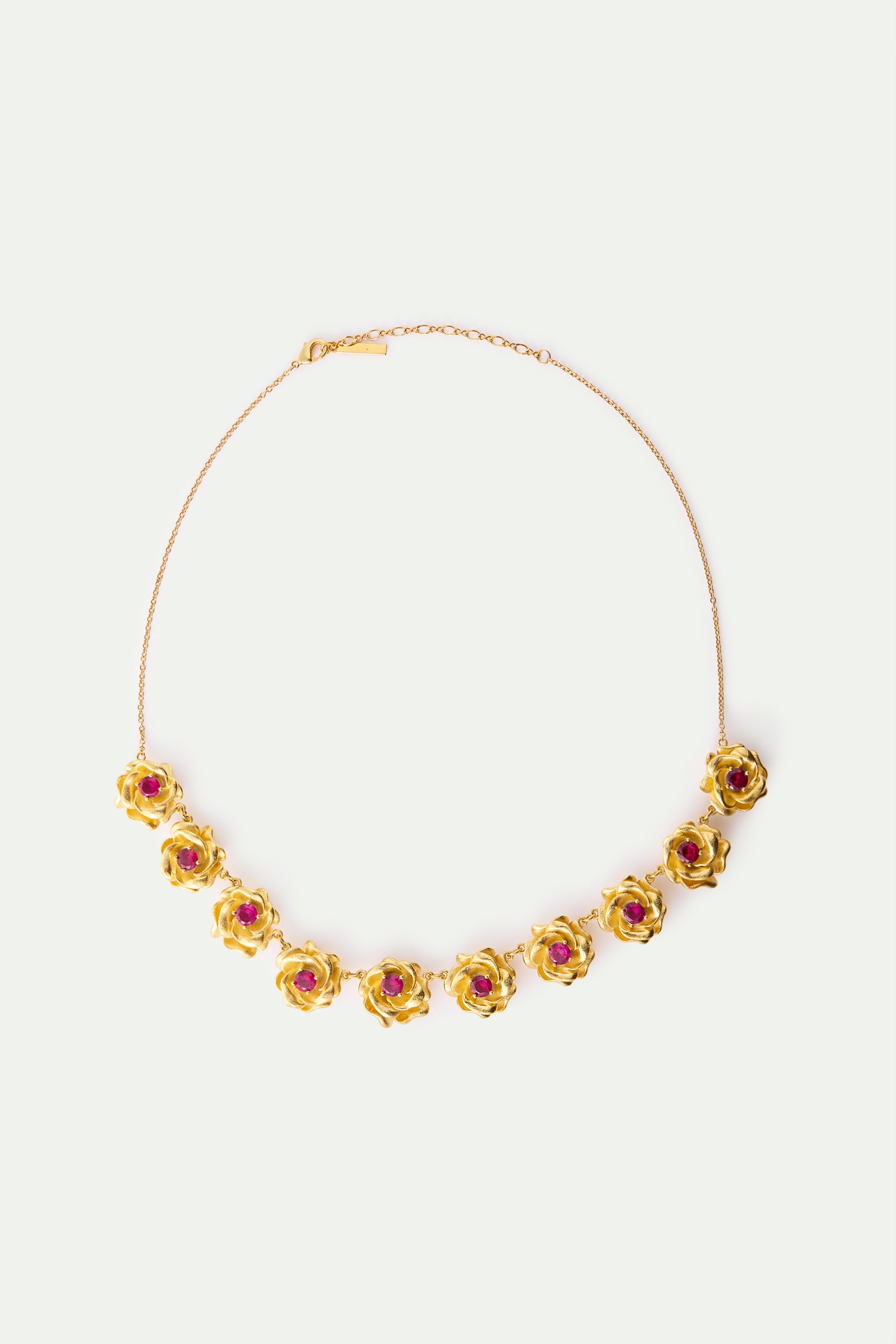 Gold-toned necklace with 11 gold-toned rose charms, each featuring a small red stone in its center.