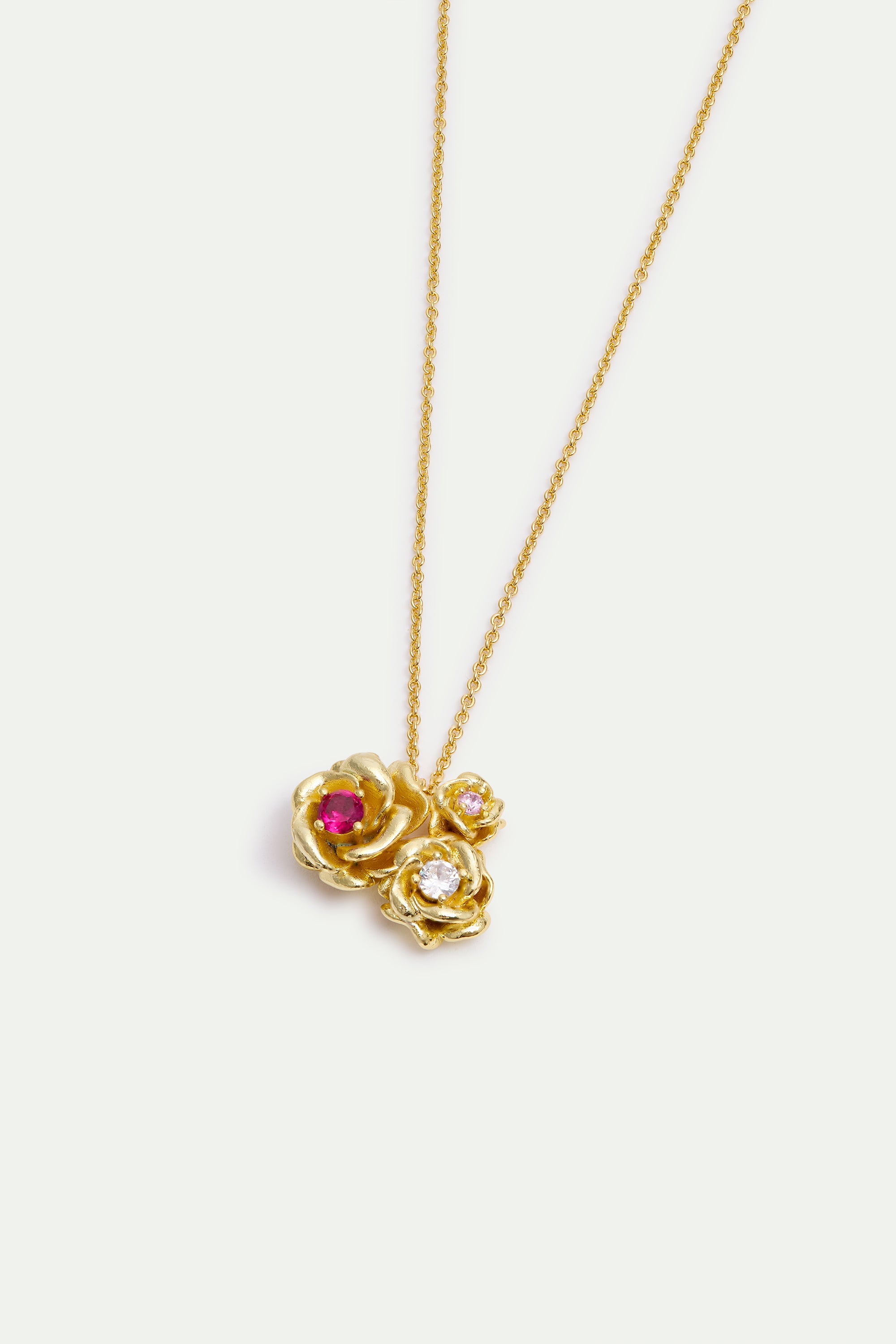 Gold-toned necklace with a pendant of three clustered roses. One rose has a red stone, another a clear stone, and the smalles
