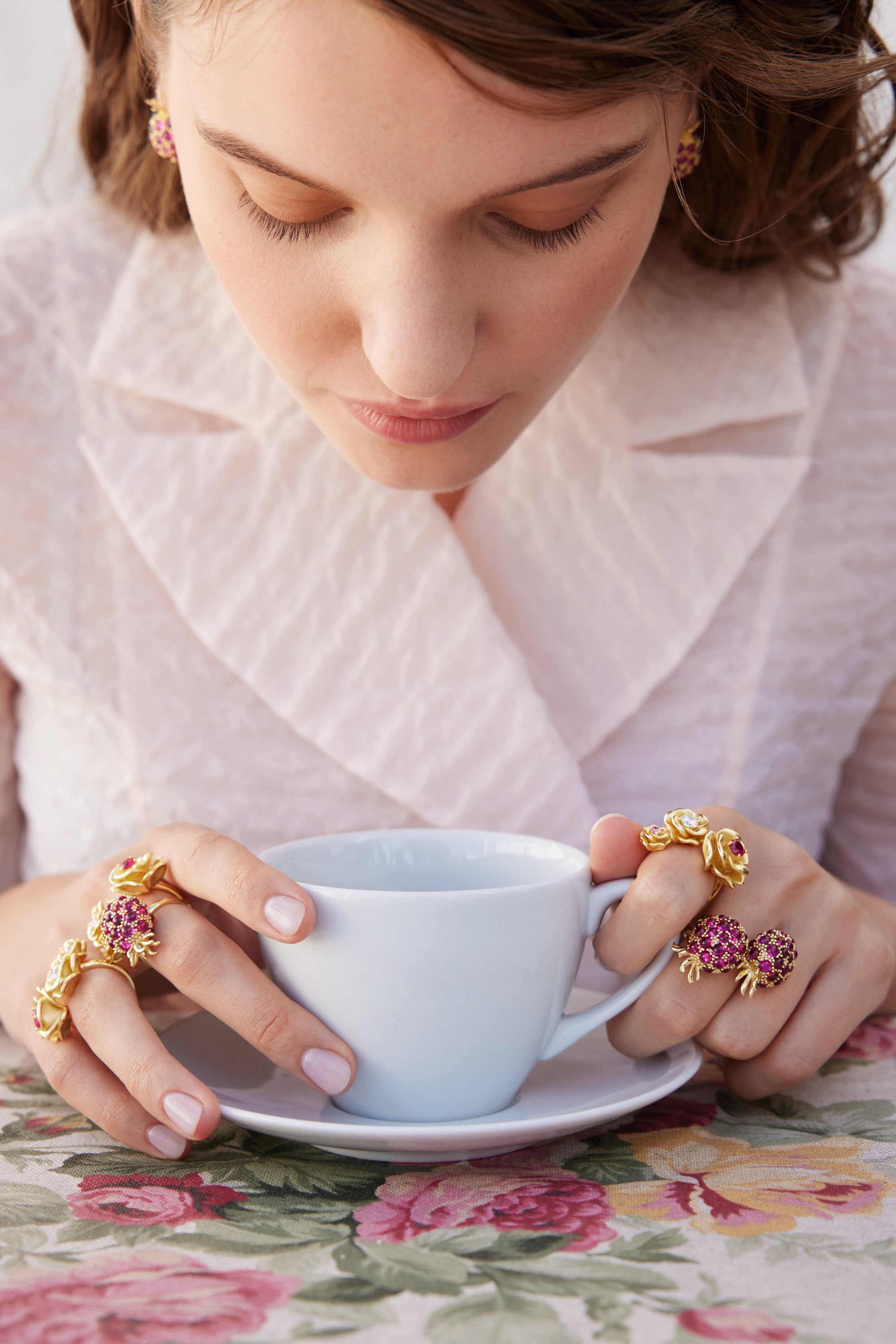 Gold-toned adjustable ring with three rose-shaped elements; one large with fuchsia stones, one small with a clear stone, one