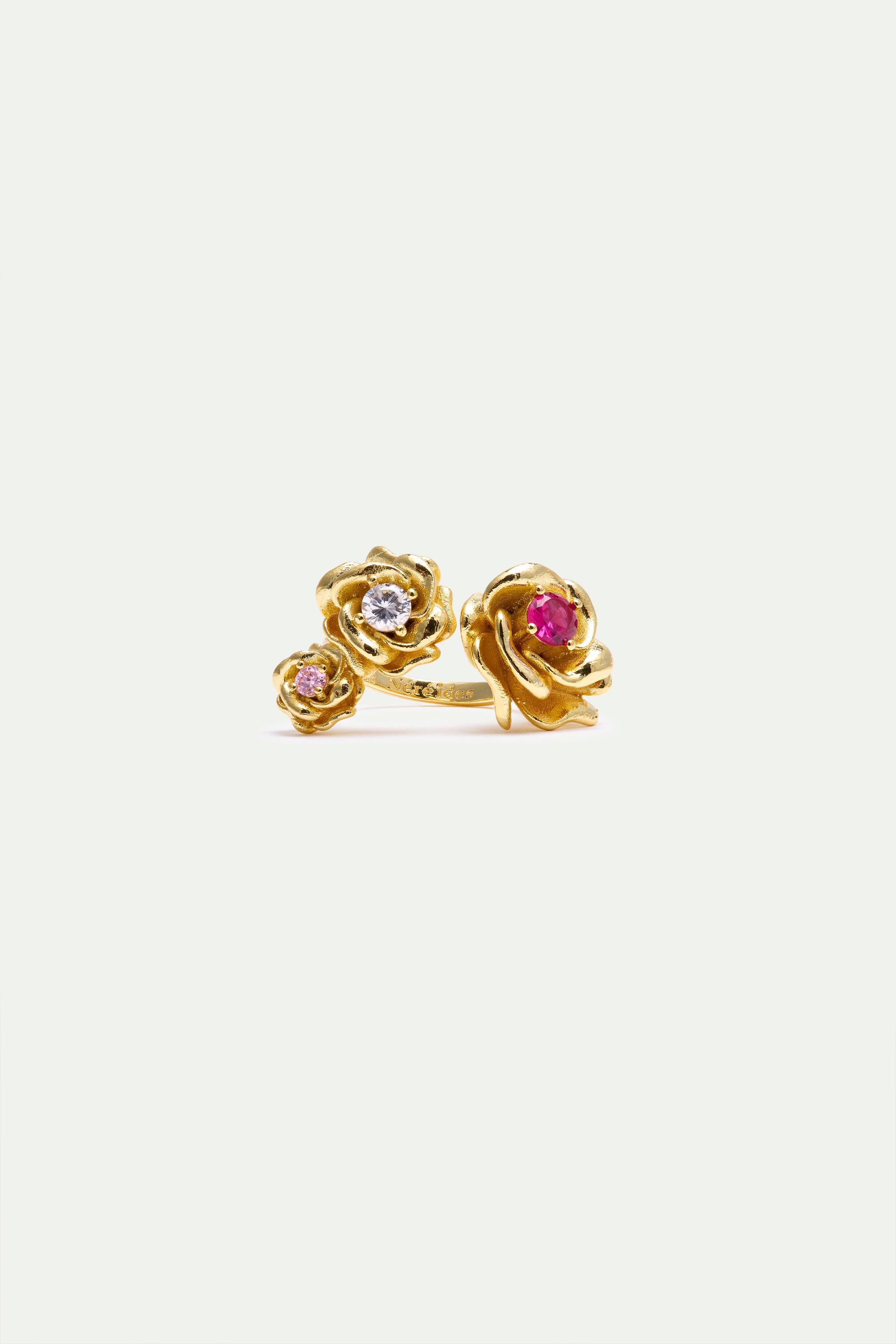Gold-toned adjustable ring with three rose-shaped elements. The largest rose has a fuchsia stone, the middle a clear stone, a