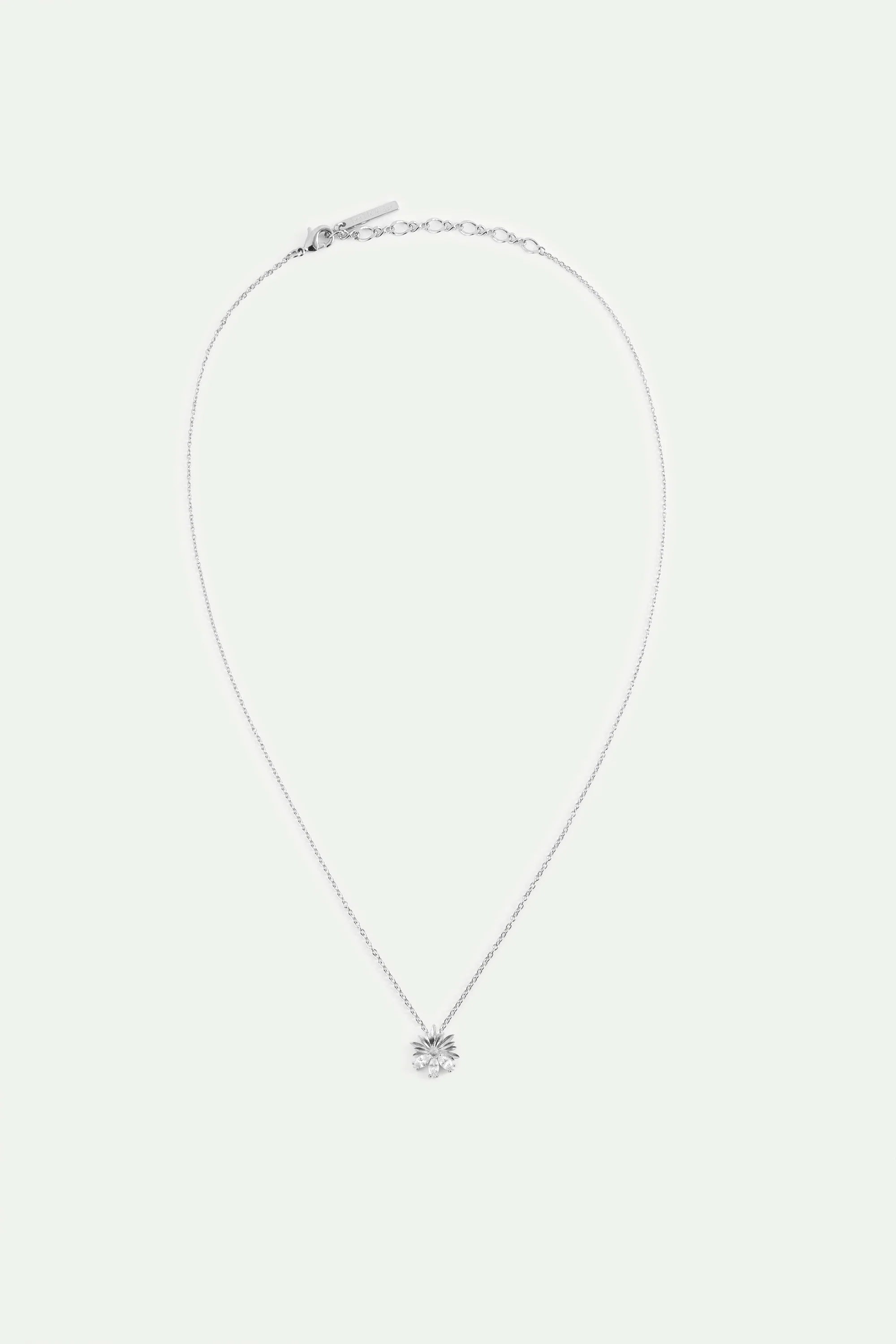 Silver-toned necklace with a thin chain and a flower pendant featuring multiple petals and three clear round stones.