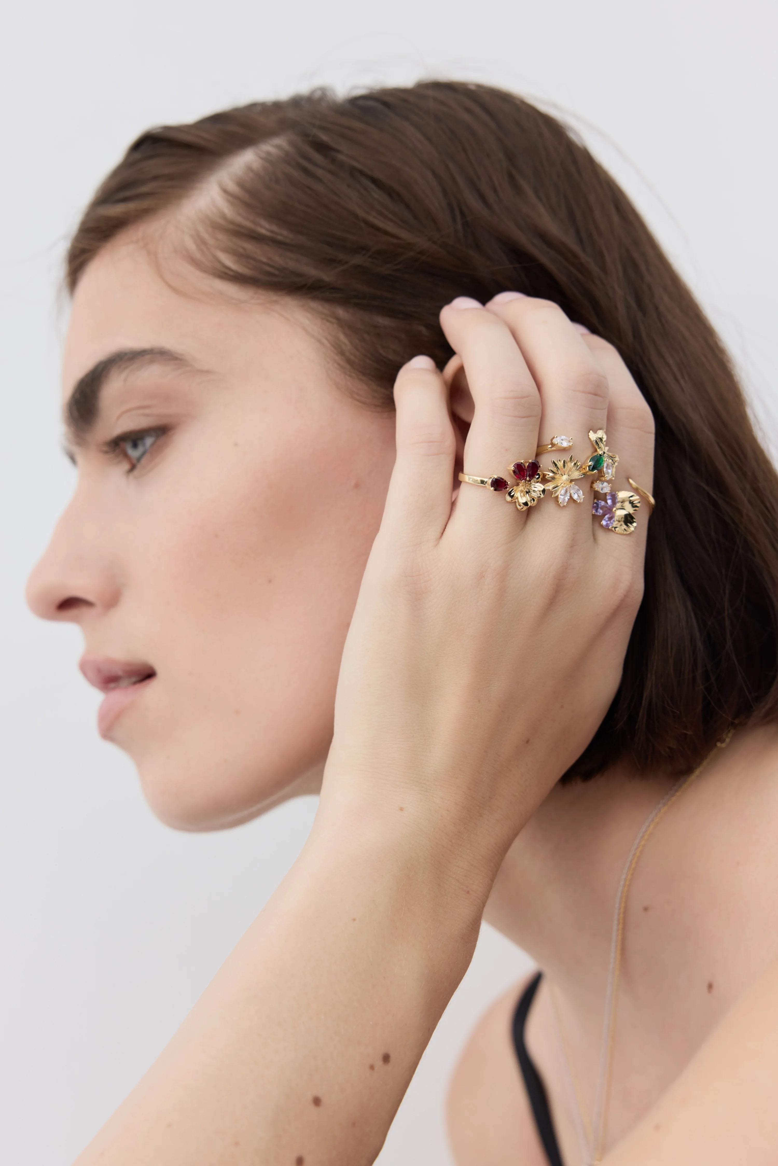 Gold-toned adjustable ring with multiple floral motifs, featuring dark red, clear, green, and purple stones.