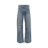 Front studio shot of Agolde wide-leg jeans in a medium wash blue, highlighting the signature asymmetrical criss-cross crossover waistband.