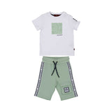 A baby boy's two-piece set featuring a white short-sleeved T-shirt and forest green shorts. The T-shirt has a centered dark green rectangular logo patch, and the shorts feature a matching logo on the left leg with a green and white braided drawstring.