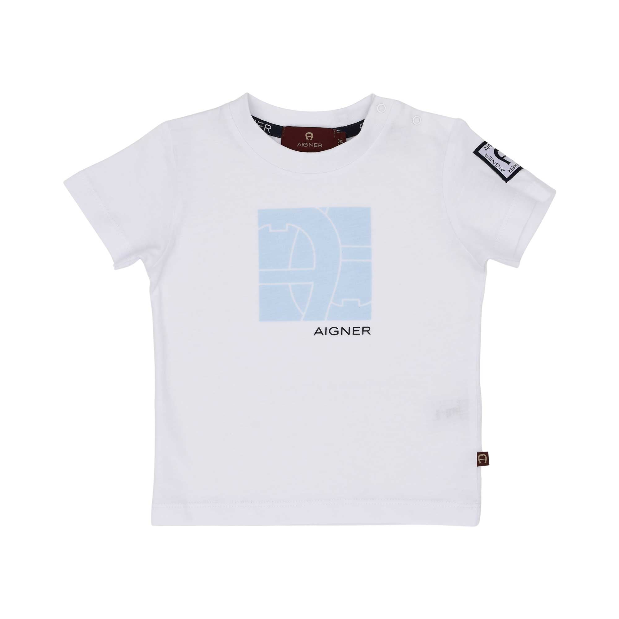 A white short-sleeved t-shirt for baby boys by Aigner Kids, featuring a light blue square graphic with the horseshoe logo and "AIGNER" printed in navy. Includes two white snap buttons on the left shoulder and a logo patch on the left sleeve.
