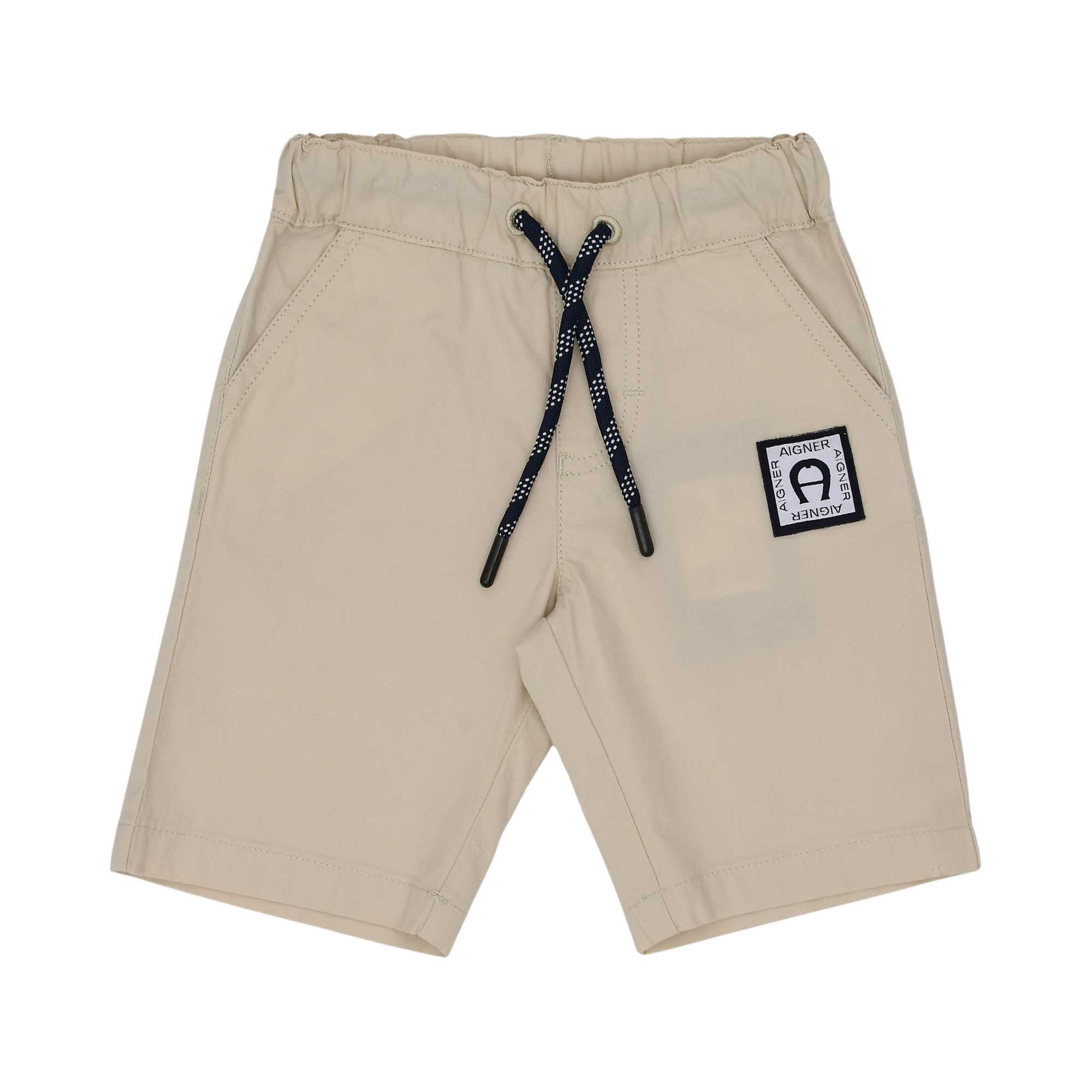 Close-up of beige Aigner Kids shorts featuring an elastic waist, navy speckled drawstring, and a black logo patch.