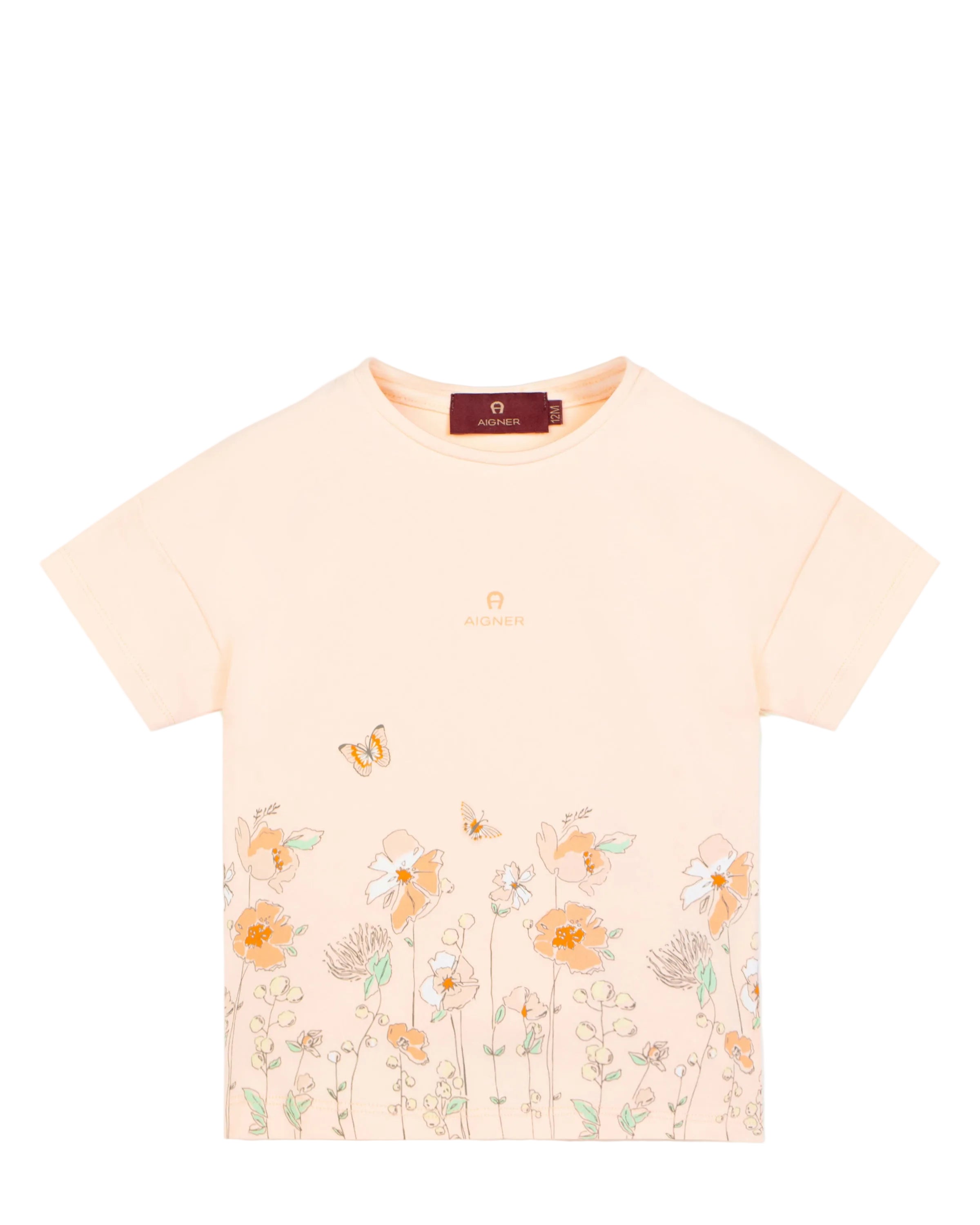 A pastel peach Aigner Kids T-shirt featuring a botanical floral and butterfly print along the bottom hem and the Aigner logo on the chest.