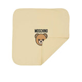 Front view of a white Moschino Kids baby blanket with one corner folded over, showing the Teddy Bear logo and black Moschino text.
