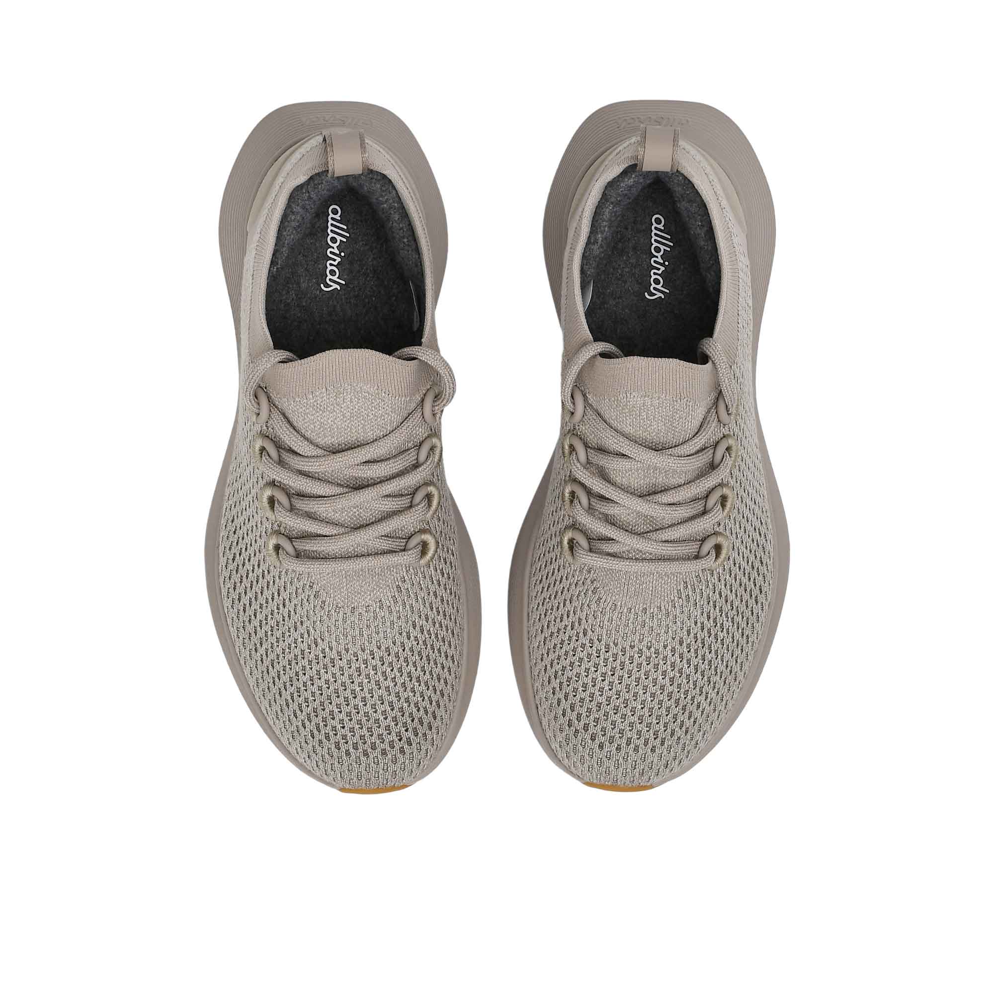 Top-down overhead view of the sneakers, displaying the dark charcoal grey insoles printed with the white Allbirds logo.