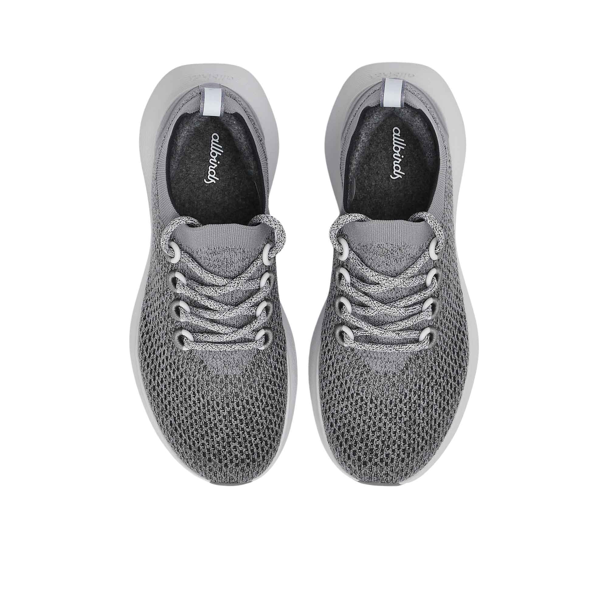 Top-down overhead view of the sneakers, displaying the dark charcoal grey insoles printed with the white Allbirds logo.
