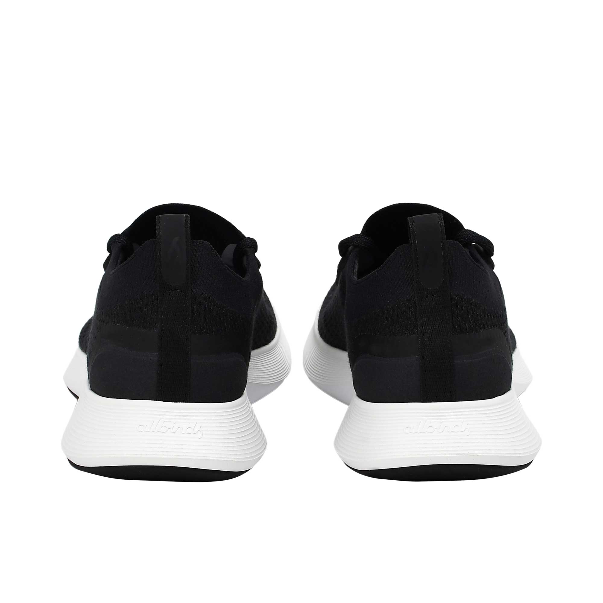 Rear view of a pair of black Allbirds Tree Runner sneakers, showing the fabric heel pull tabs and the subtle embossed "allbirds" branding along the white textured heels.