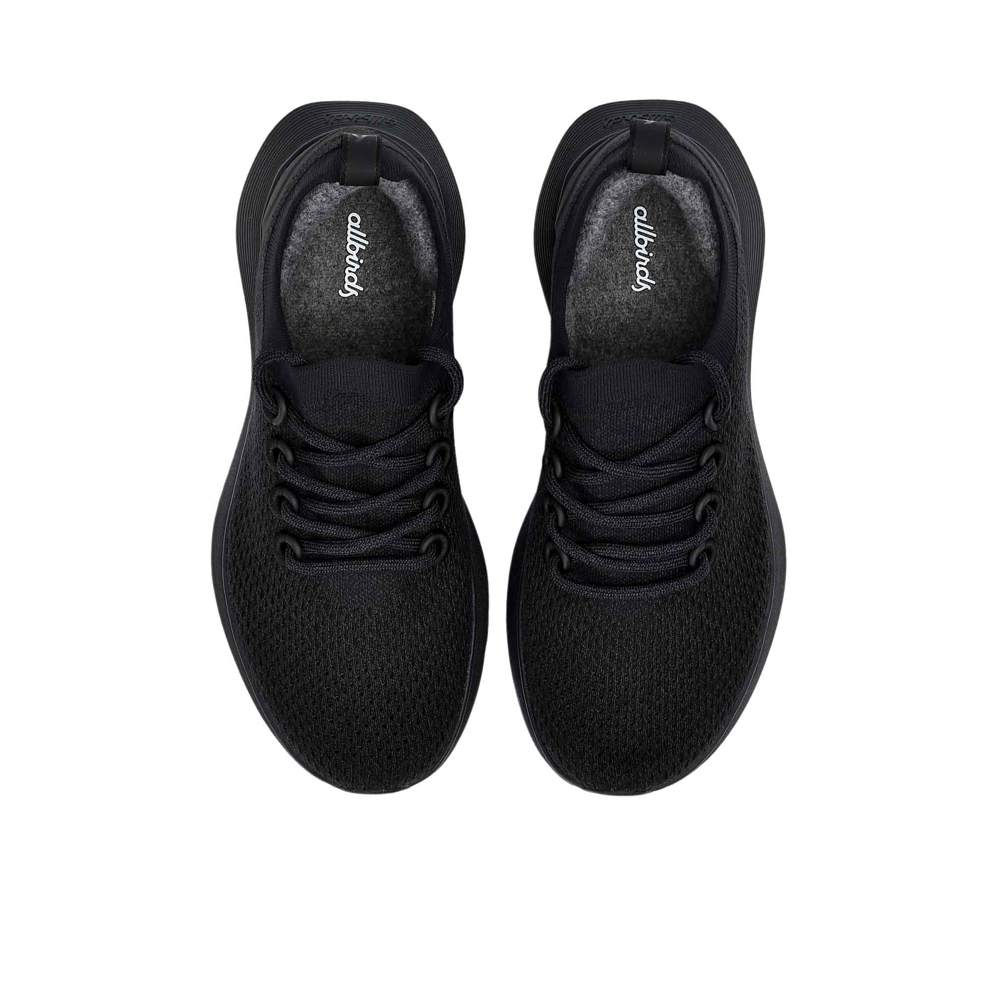 Directly overhead top-down view of a pair of black Allbirds Tree Runner sneakers, highlighting the gray insoles with the printed cursive "allbirds" logo.