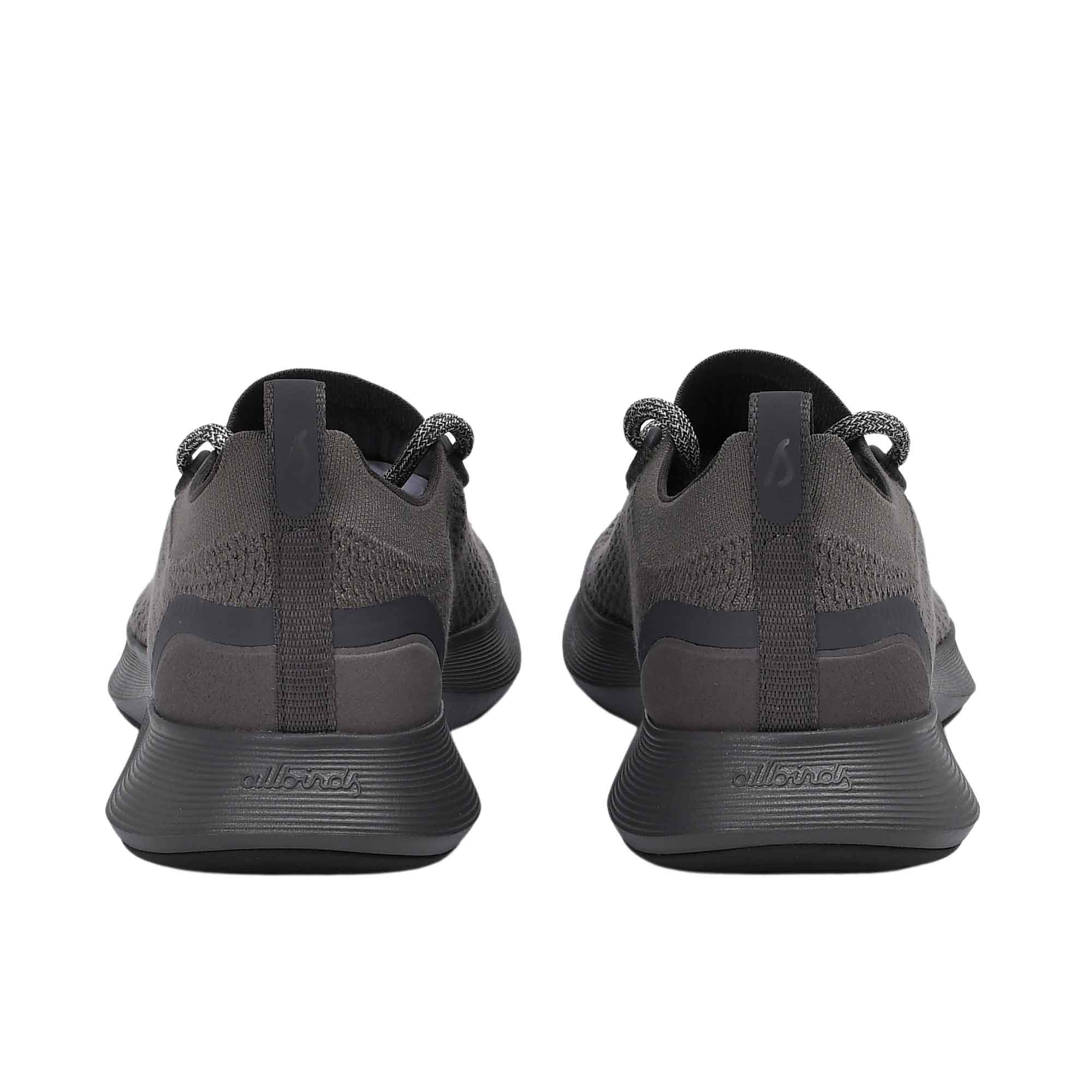 Rear view of the heels of the Allbirds Tree Dasher 2 sneakers, showcasing the flared midsole geometry and the embossed "allbirds" logo on the lower heel.