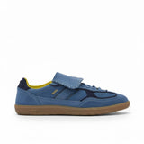 Profile view of a low-top blue suede sneaker featuring a large fold-over lace flap, navy blue heel trim, a vibrant yellow interior lining, and a classic brown gum sole.