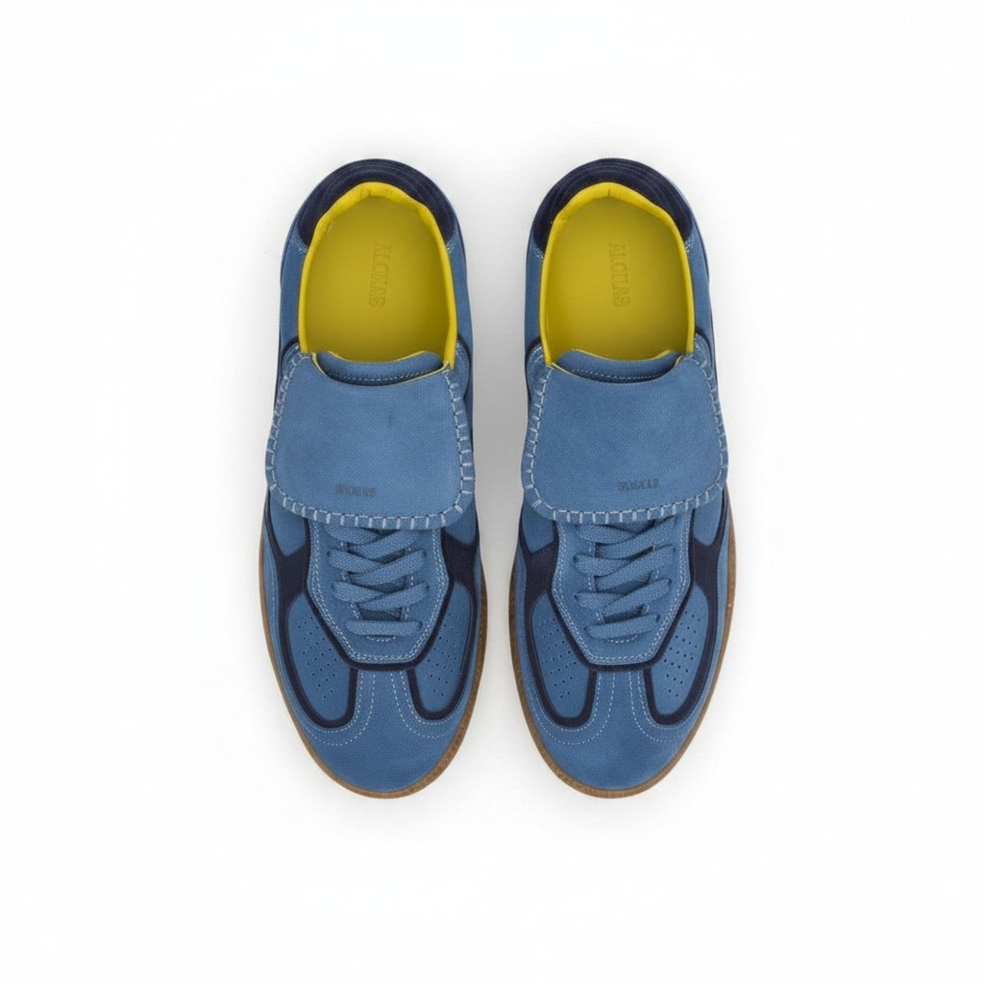 High-angle view of the pair of blue suede shoes, displaying the large lace covers, wavy navy blue side overlays, and contrasting bright yellow insoles.