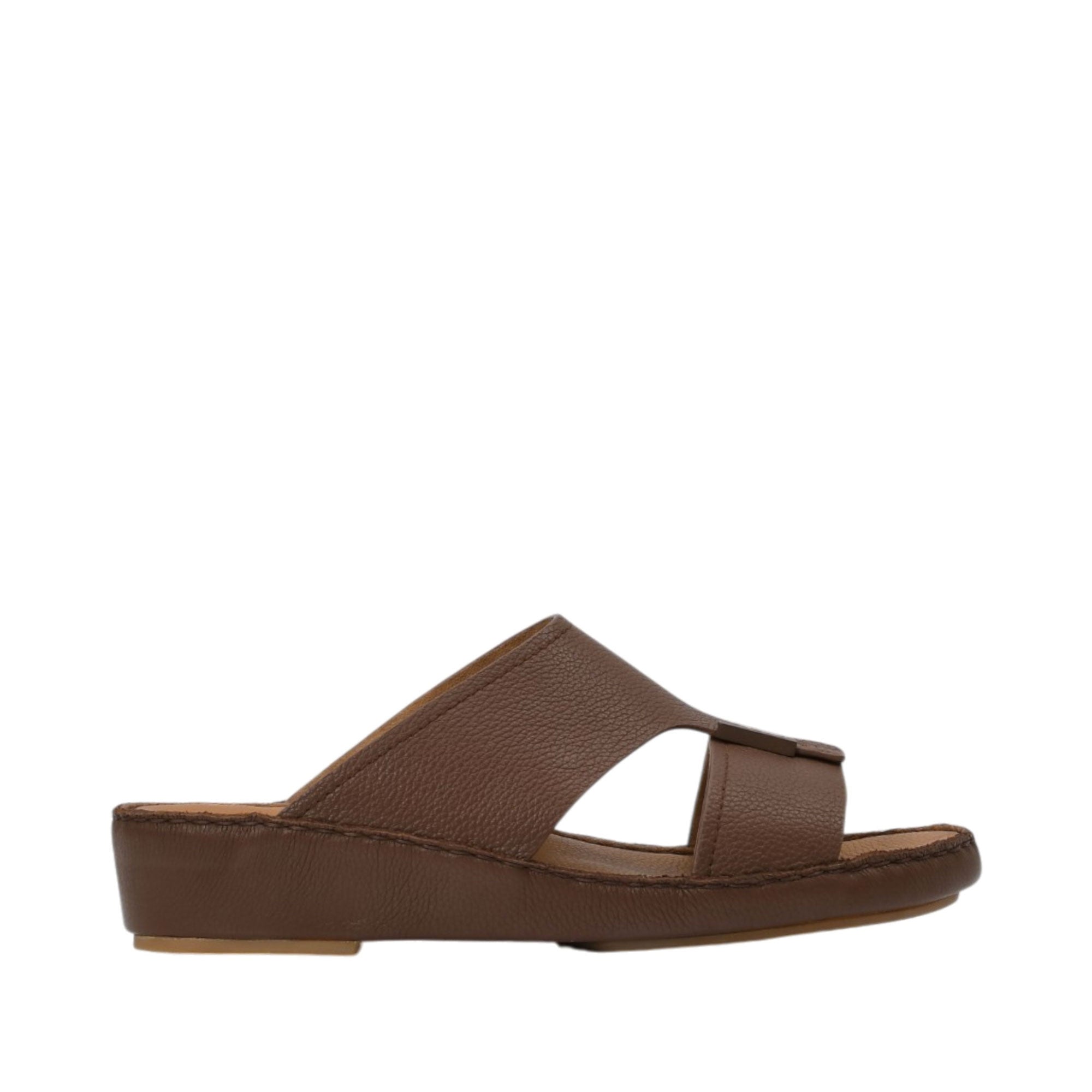 Profile view of an Antonio brown grained leather Arabic sandal, showing its broad cross-strap upper design and matching leather-wrapped platform wedge sole against a white background.