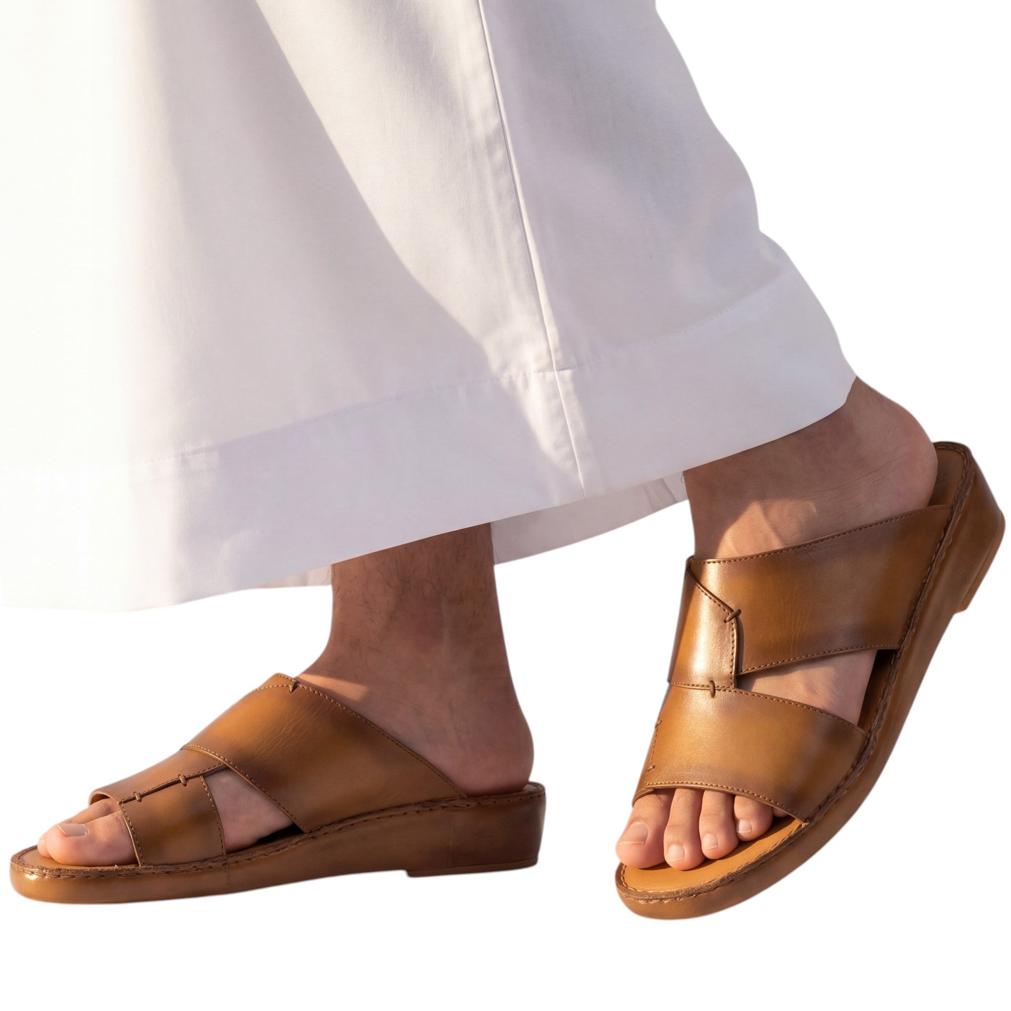 On-model studio shot showcasing the Antonio tan burnished leather Arabic sandals being worn with a traditional flowing white thobe against a white background.