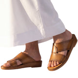 On-model studio shot showcasing the Antonio tan burnished leather Arabic sandals being worn with a traditional flowing white thobe against a white background.