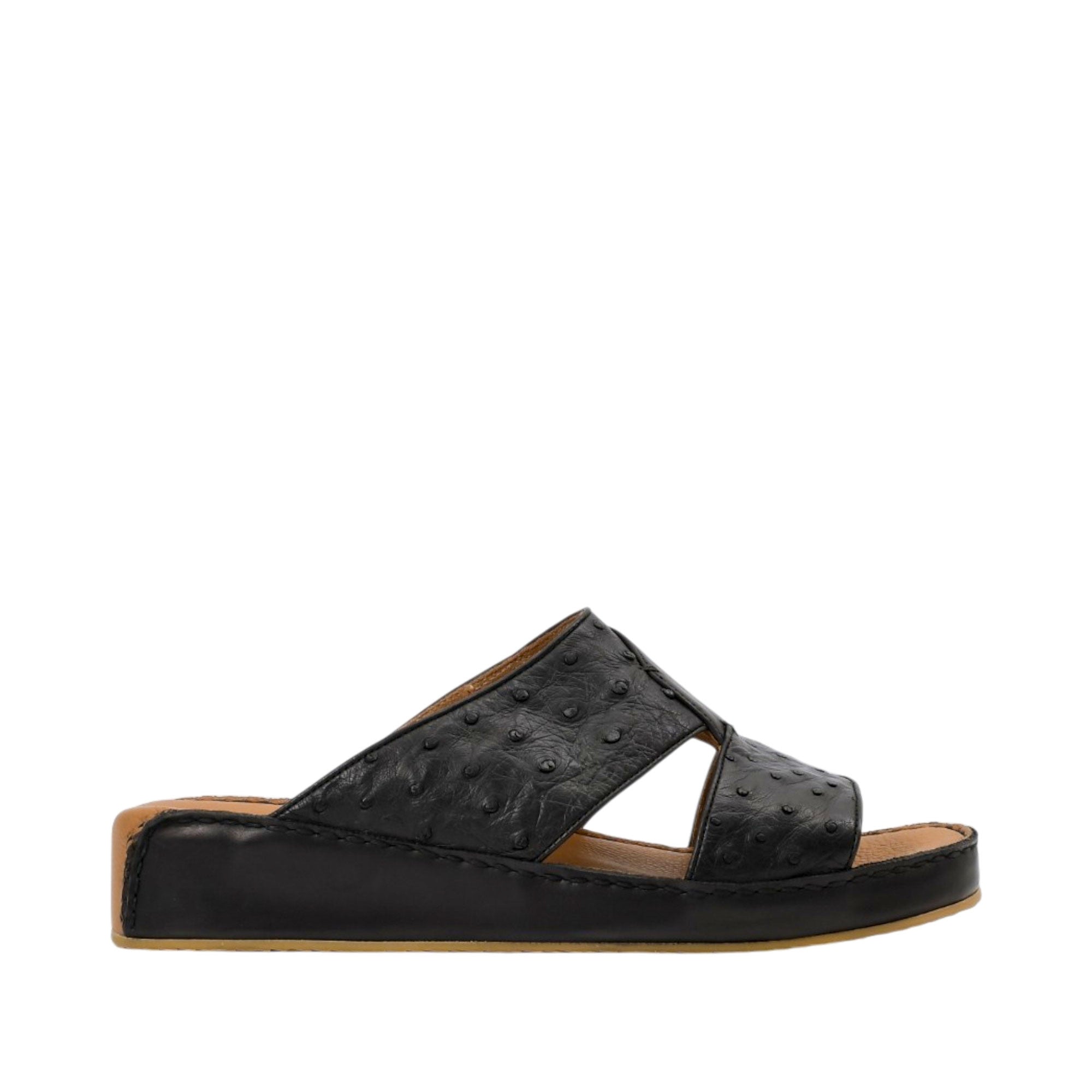 Profile view of an Antonio black leather Arabic sandal, showcasing the ostrich-effect textured cross-strap upper and the tonal leather-covered wedge sole against a white background.