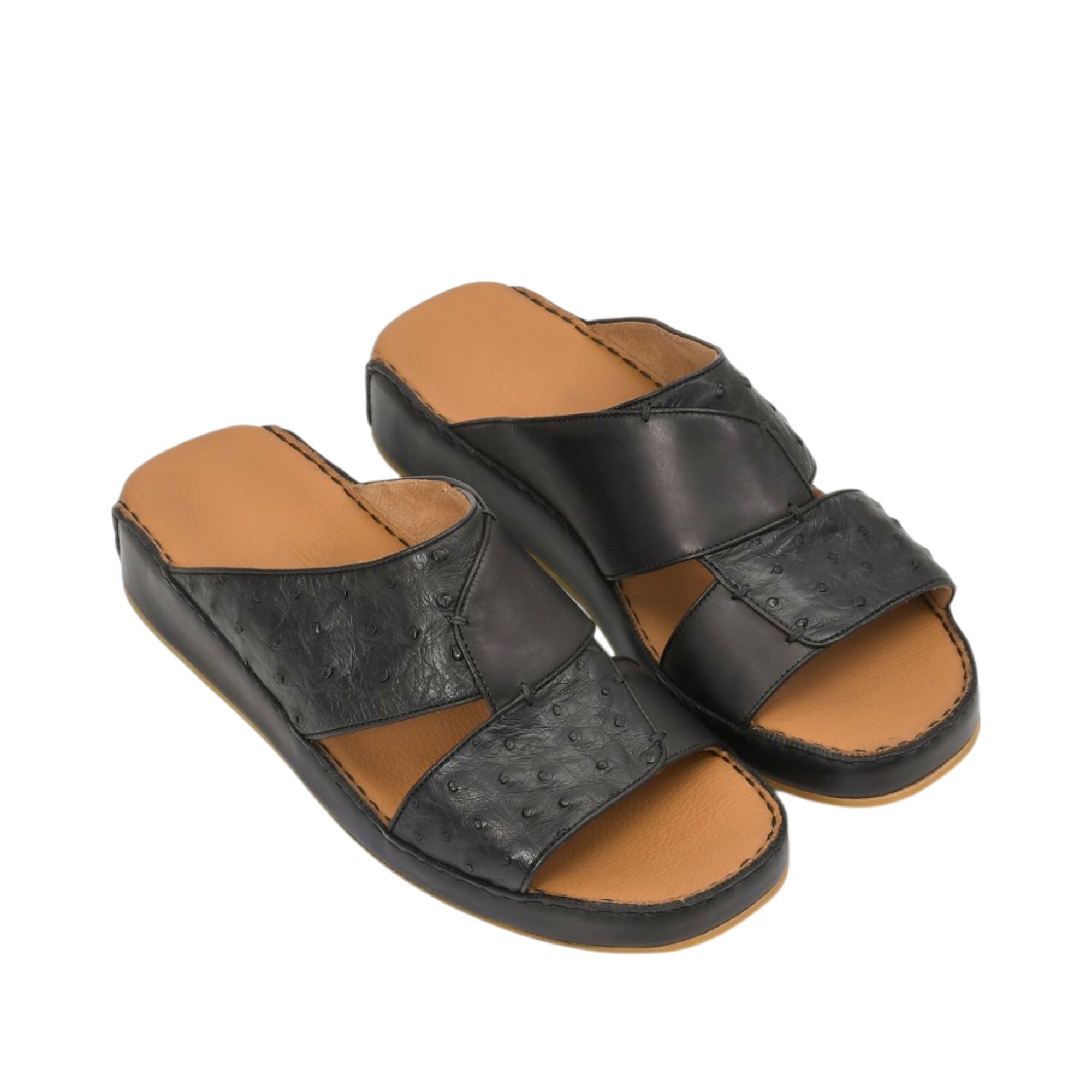 An overhead three-quarter angle view of a pair of Antonio black leather sandals, demonstrating the rich blend of smooth and ostrich-textured finishes against a white background.