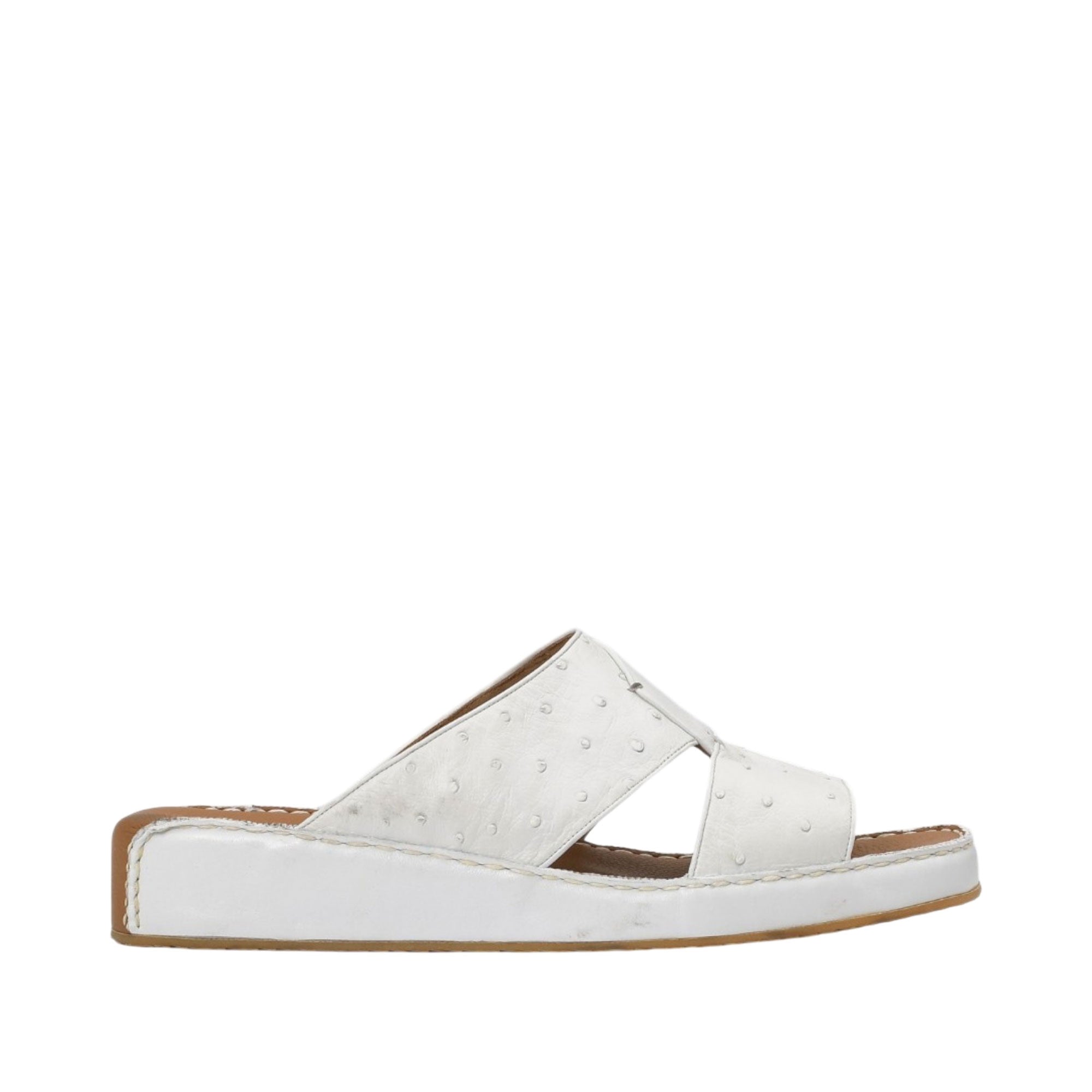 Profile view of an Antonio white leather Arabic sandal, showcasing the ostrich-effect textured cross-strap upper and the tonal leather-covered wedge sole against a white background.