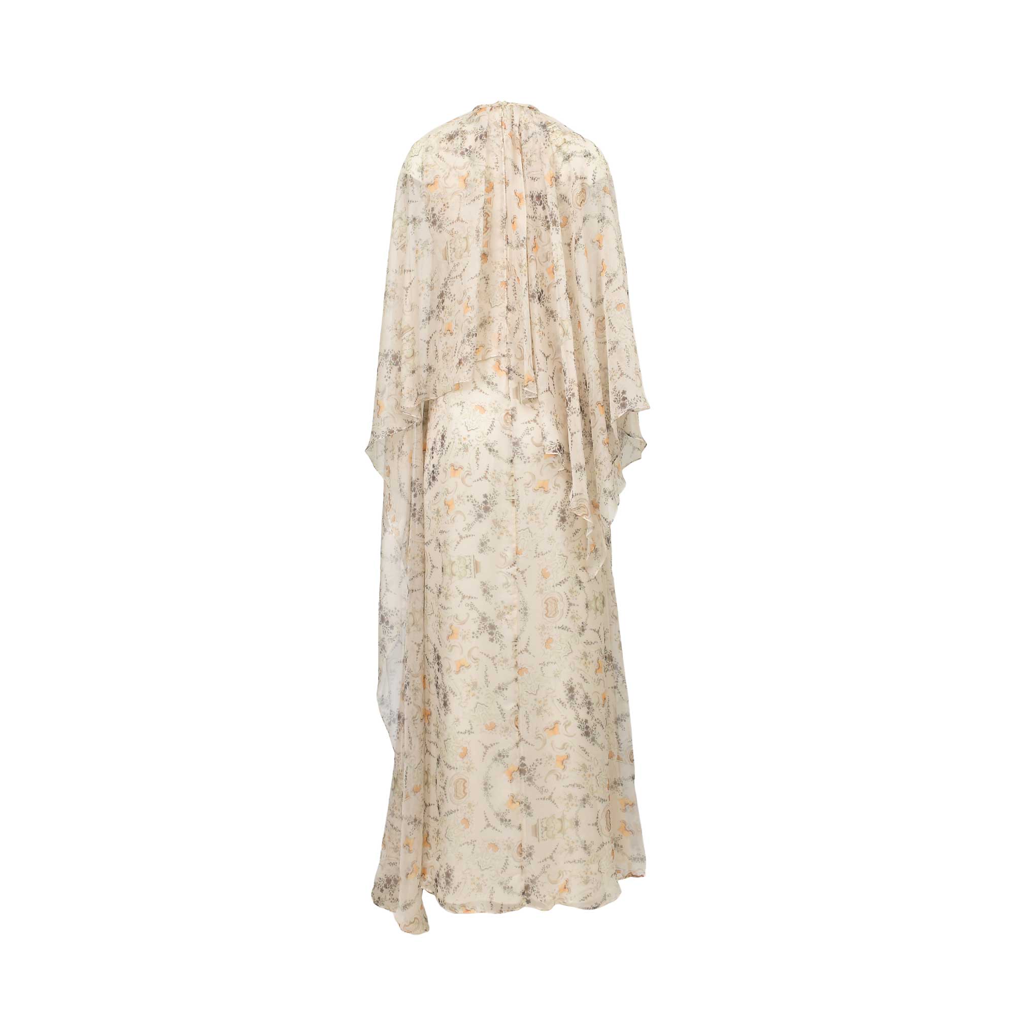 Cream maxi dress with a muted floral pattern in orange, grey, and green. Features a high gathered neckline and a flowing cape