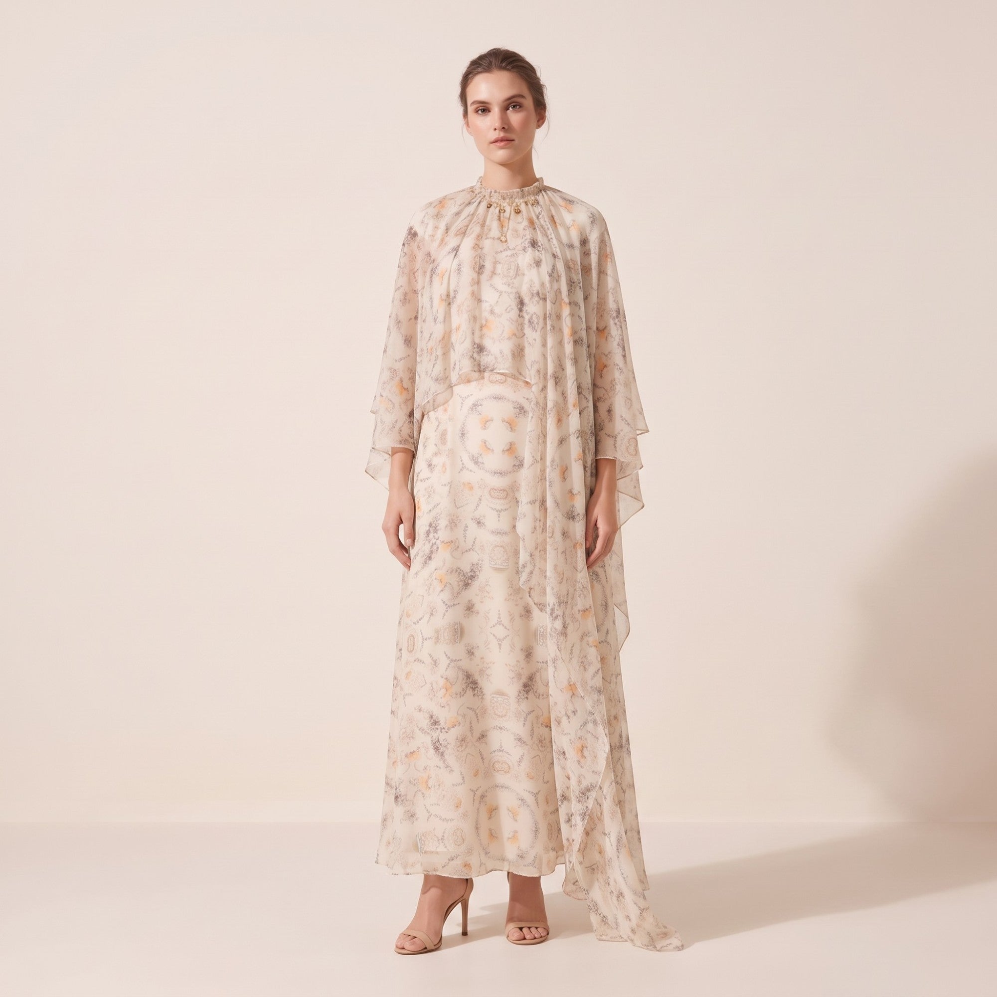 Sheer off-white dress with a high gathered neck, gold-toned embellishments, and a flowing cape overlay, featuring an orange a