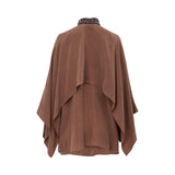 Back view of BAQA cape-overlay blouse in mocha, showing the architectural drape and embellished collar detail