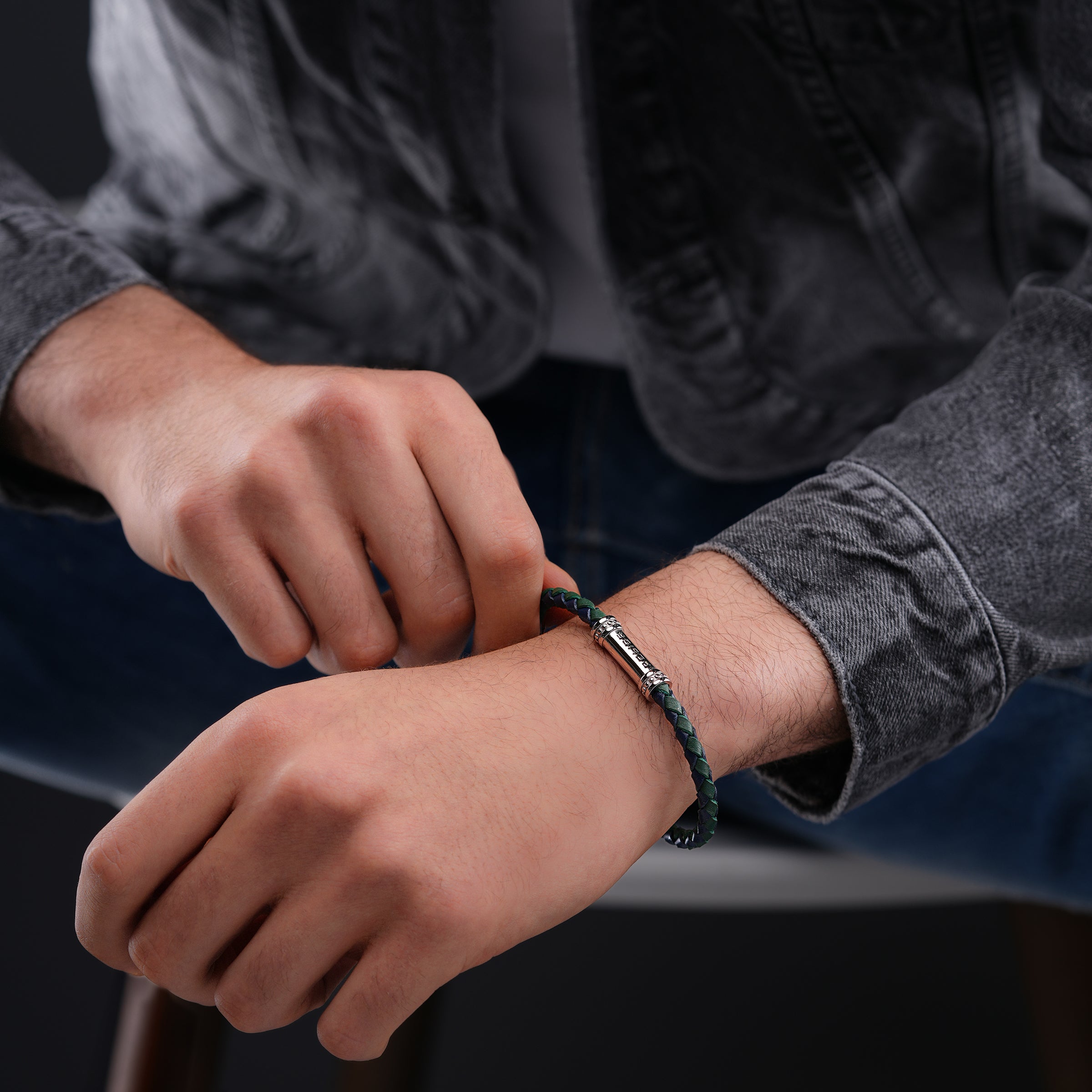 Braided blue-green bi-leather bracelet with a silver-toned barrel-shaped magnetic clasp adorned with clear stones.