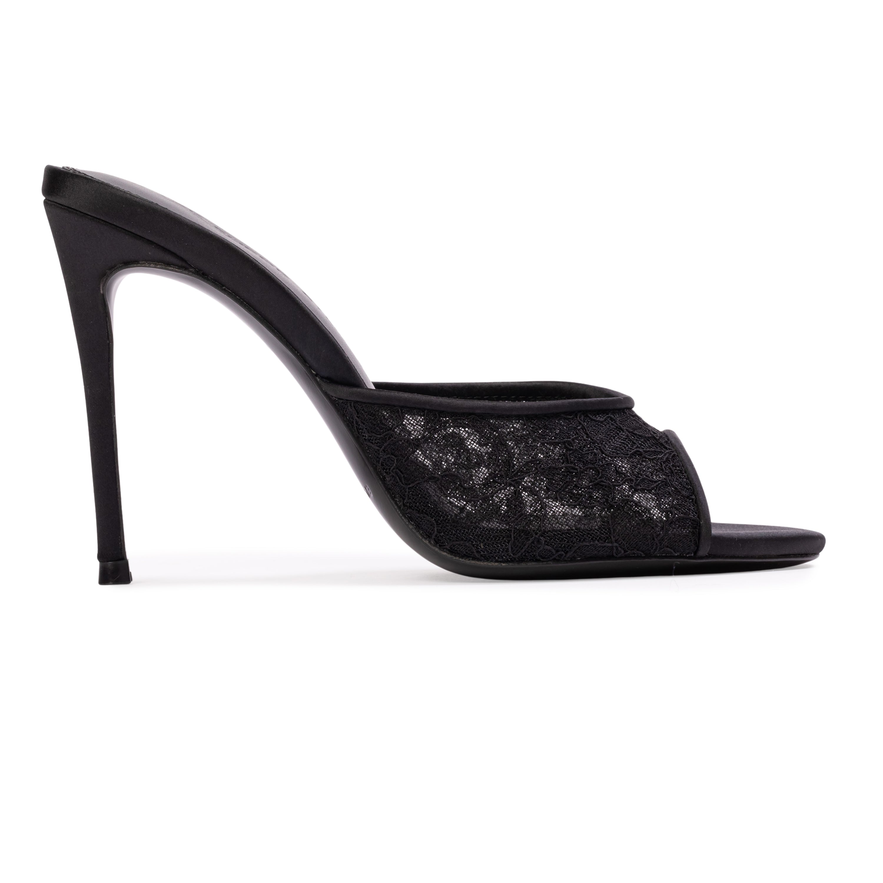 A clean, side silhouette product shot showing the outer side of the black mule, detailing the continuous line from the satin heel cup down to the thin 100mm heel.