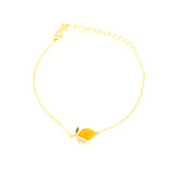 Gold-toned chain bracelet with a bright yellow lemon-shaped charm, featuring a green leaf and a segment embellished with clea