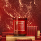 A lit Baccarat Rouge 540 scented candle in a deep red glass jar with a gold-toned label.
