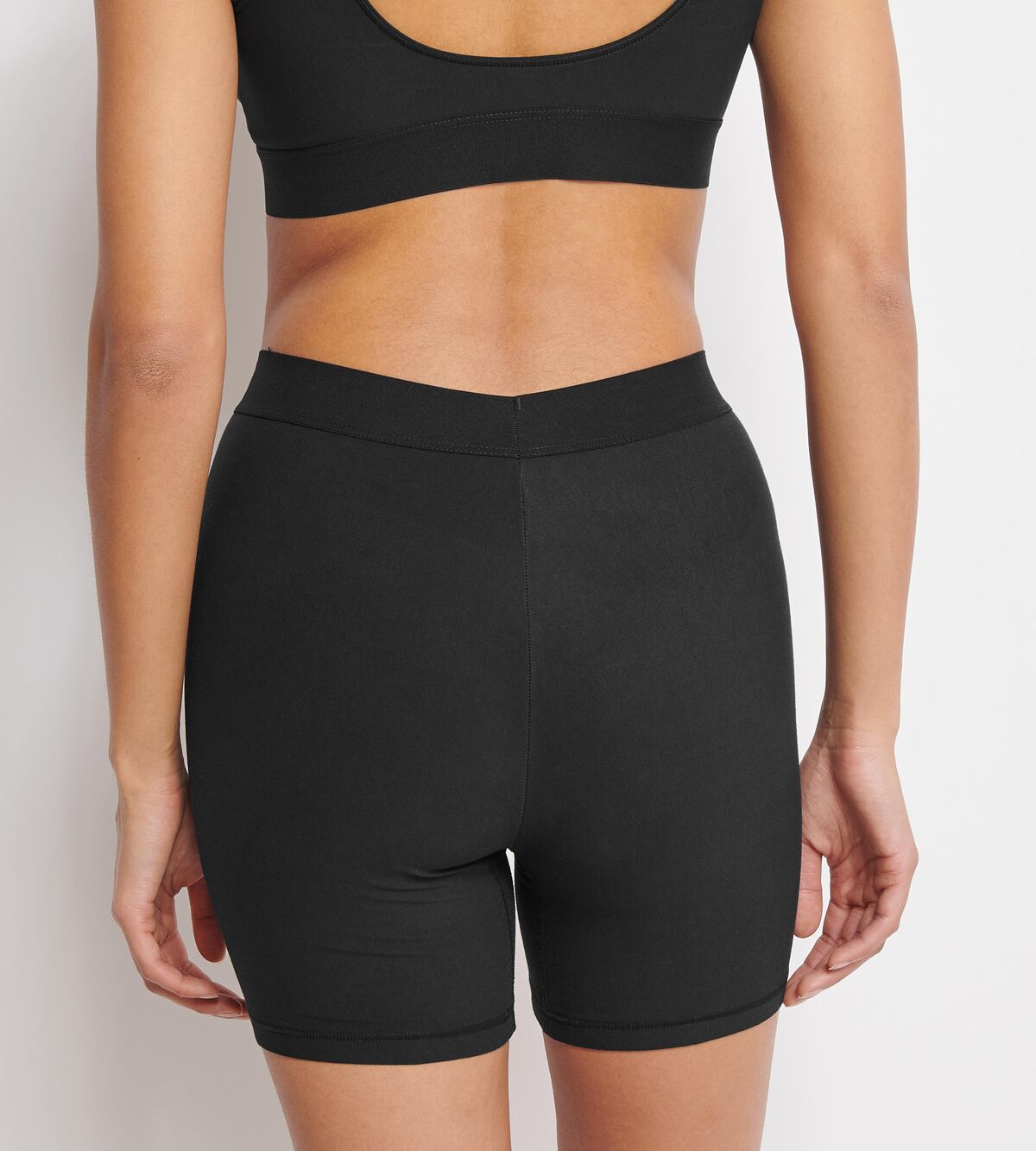 Back view of model wearing the Sloggi Ever Ease black cyclist shorts, showcasing the mid-thigh length and smooth, seamless construction. Shop the Latest Online