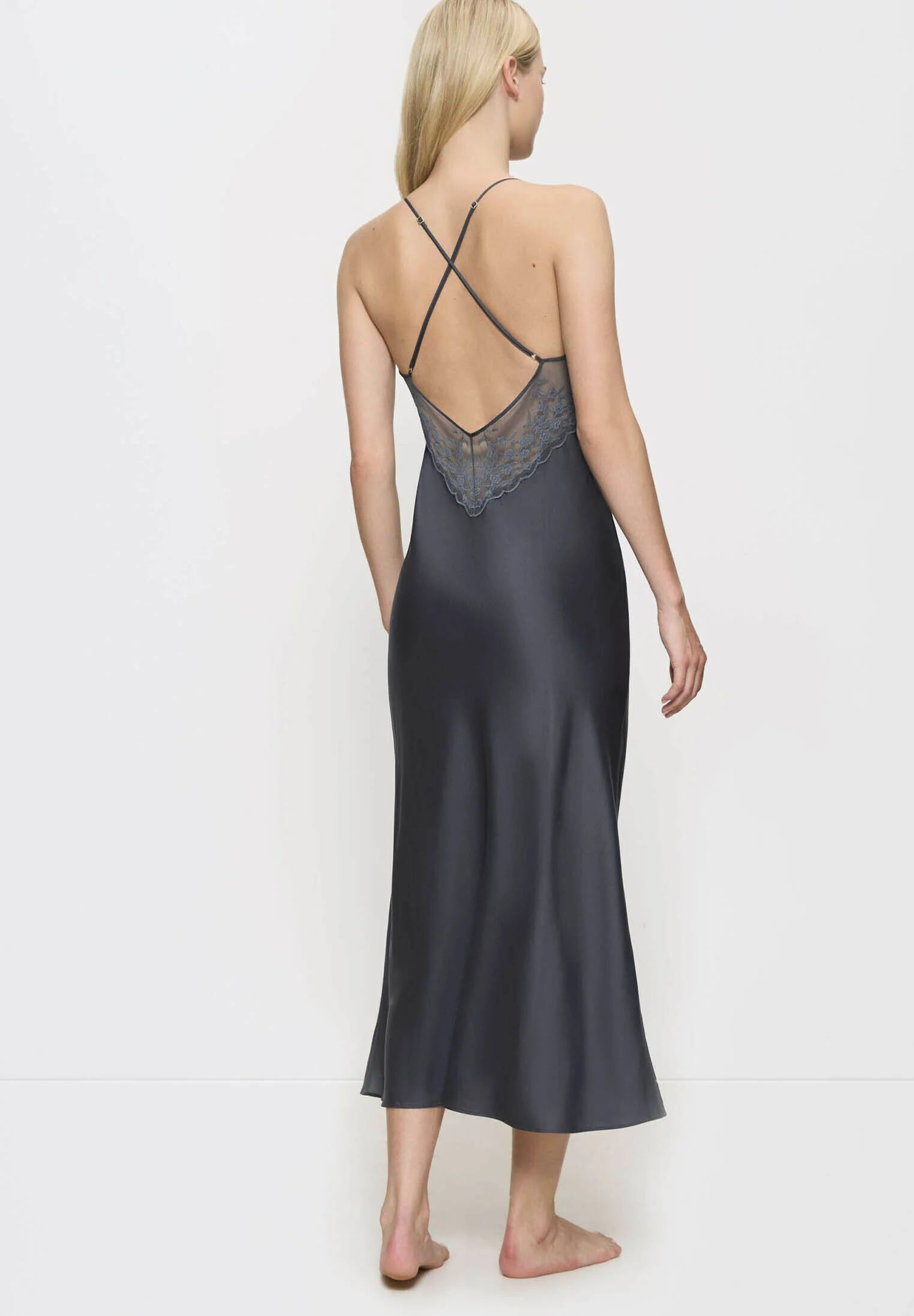 Back view of model wearing the Triumph Silky Sensuality dark grey nightdress, highlighting the cross-back straps and silky fabric drape. Find Online Now