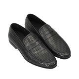 An overhead three-quarter angle view of a pair of Baldinini black woven loafers, displaying the intricate diamond-like leather texture and the subtle tonal logo on the penny strap against a white background.
