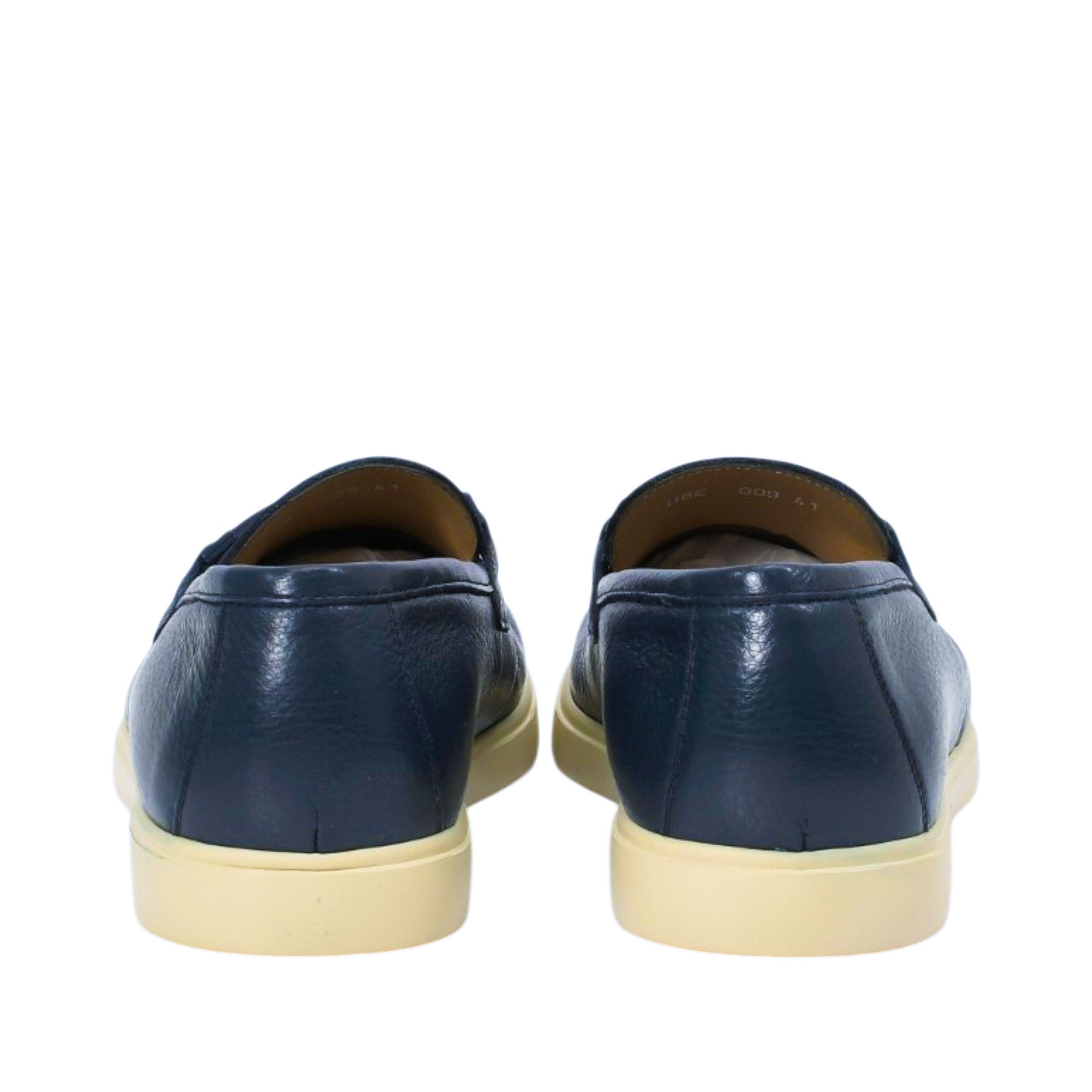 Rear view of a pair of Baldinini navy loafers, showing the clean grained leather heel counter seams and the flat, supportive profile of the cream-beige rubber sole against a white background.