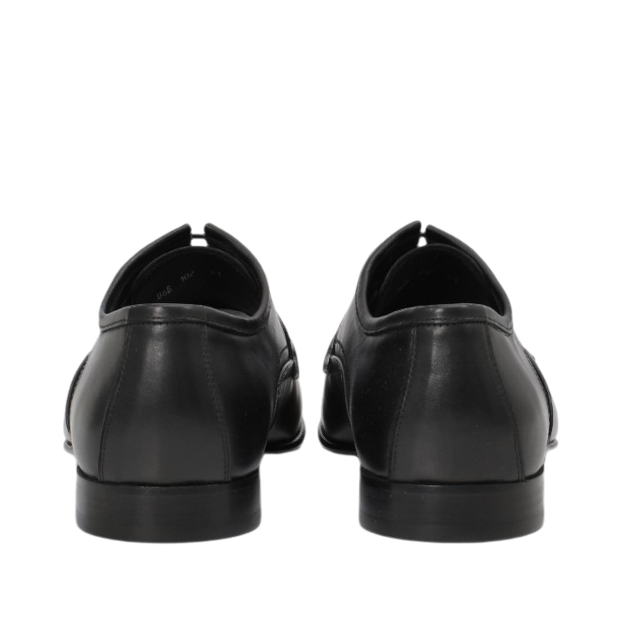 Rear view of a pair of Baldinini black Derby shoes displaying the sturdy, structured leather heel counters and clean, low-profile black block heels against a white background.