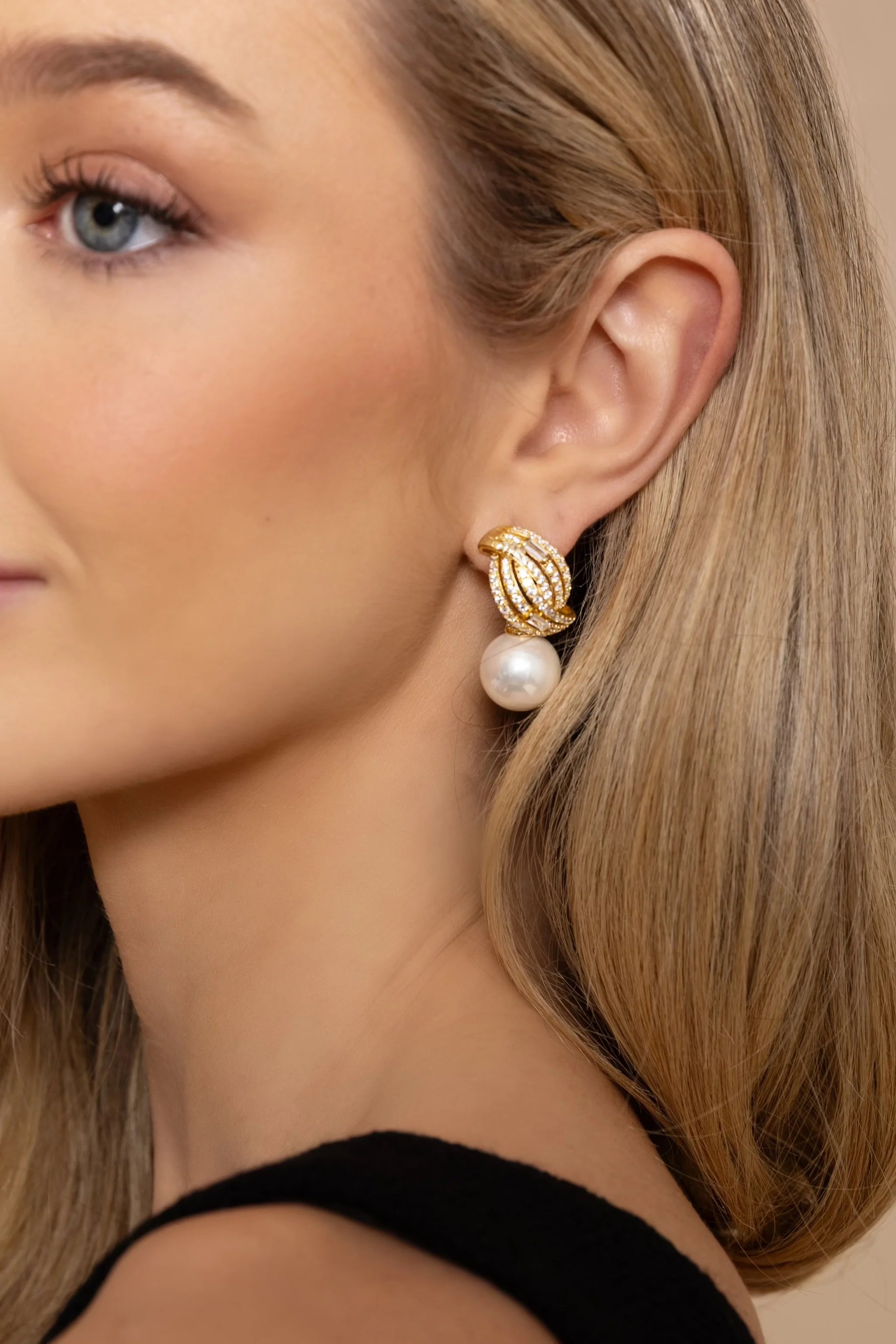 Gold-toned drop earring with intertwined, clear stone-encrusted top and a large white pearl.